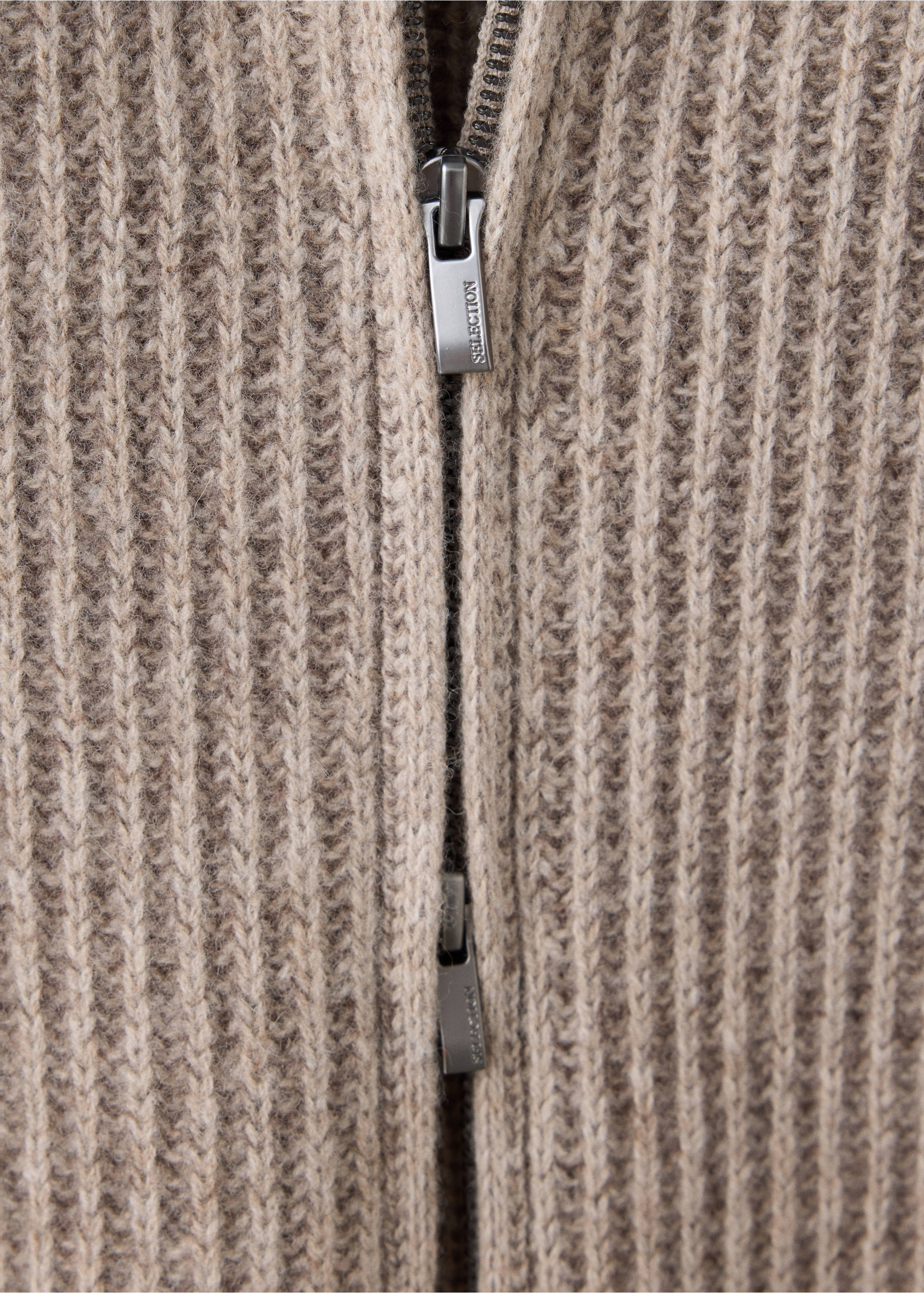 Close-up of a beige ribbed knit cardigan with a metallic zipper., Beige. Ref: 37088273-00.