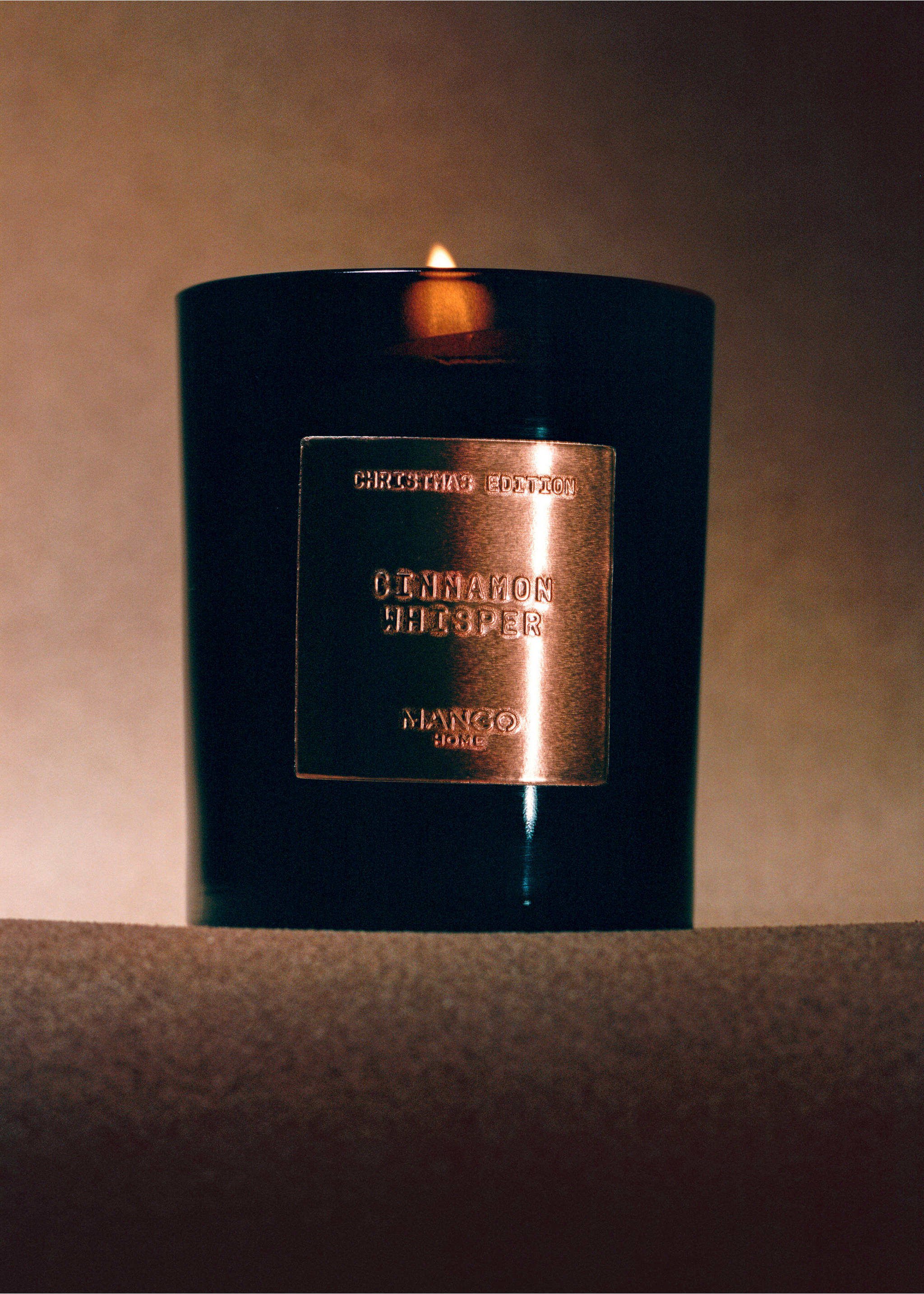 Lit scented candle in a dark glass jar with a metallic label., Copper. Ref: 37088277-00.