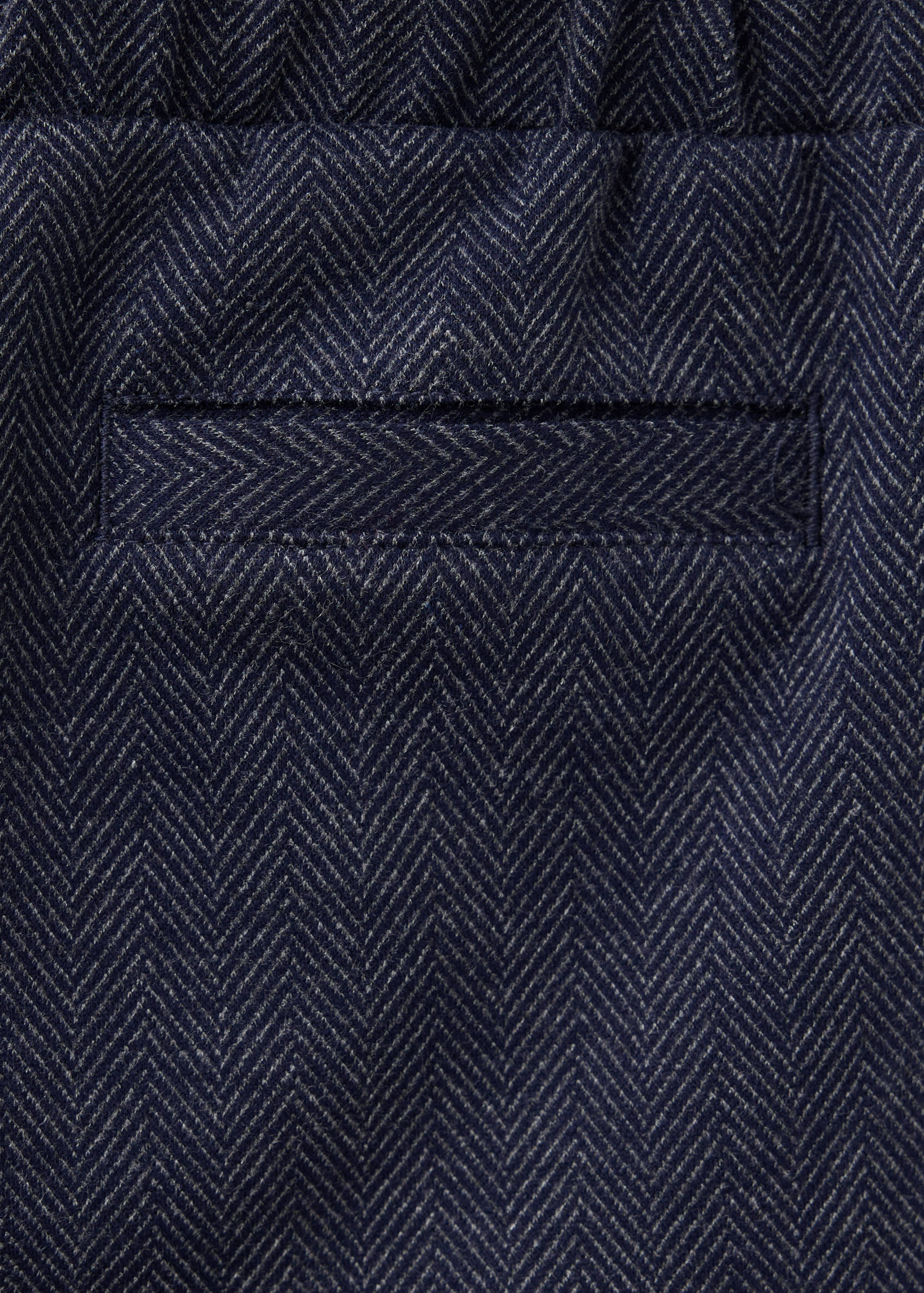 Navy blue and white herringbone trousers fabric detail.
