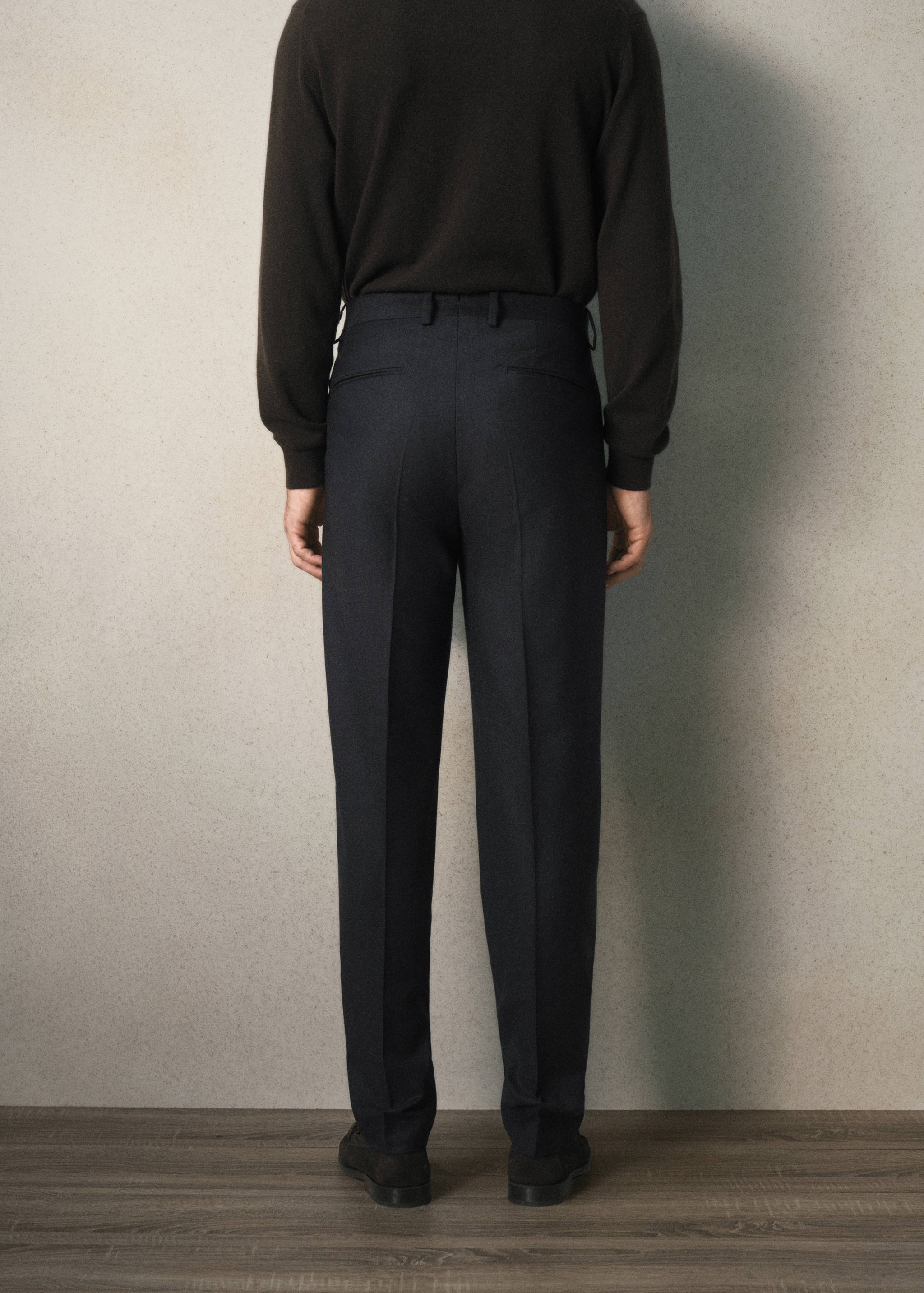Back view of dark navy blue trousers with belt loops and pressed creases.