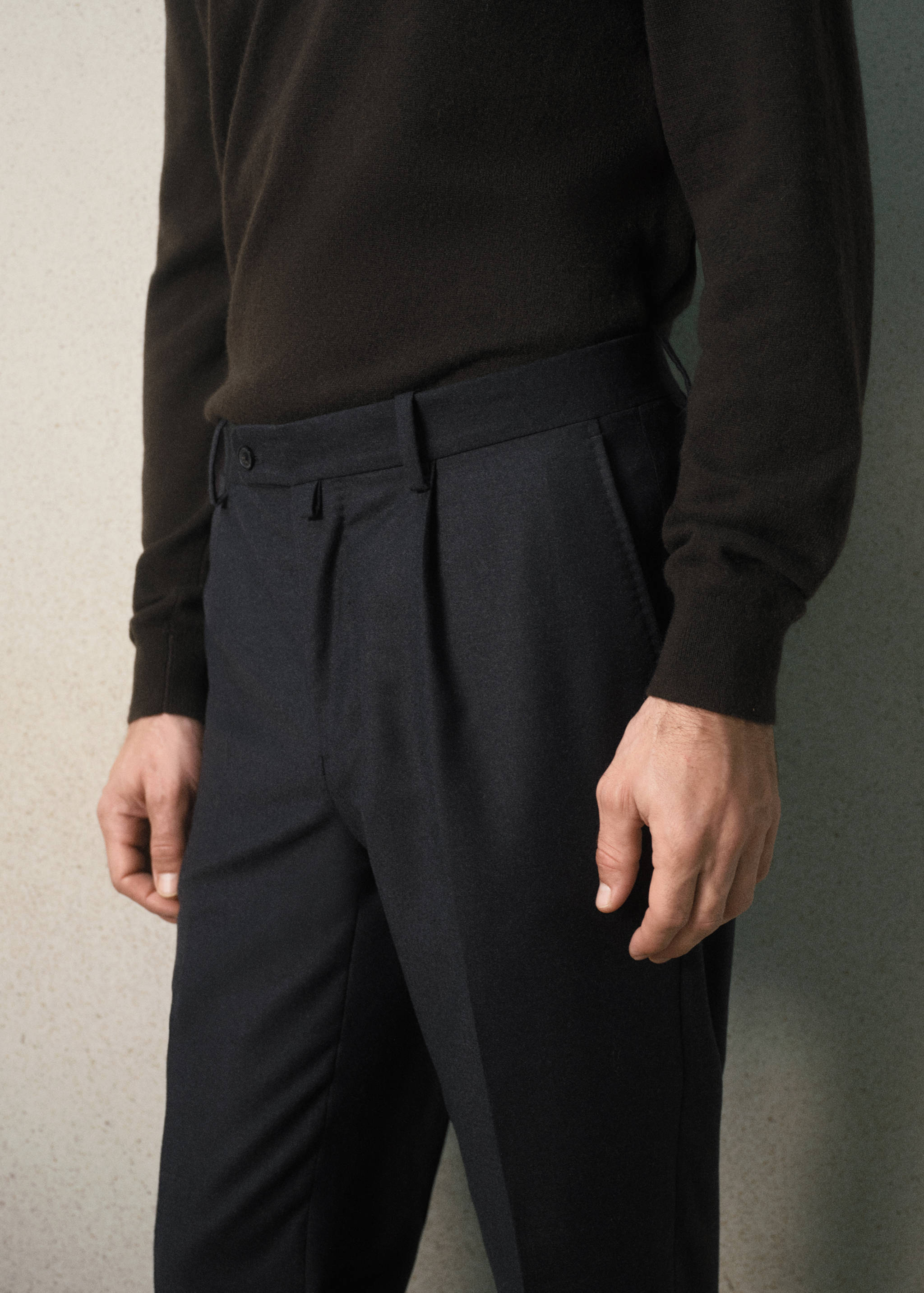 Dark grey pleated trousers worn with a dark brown sweater.