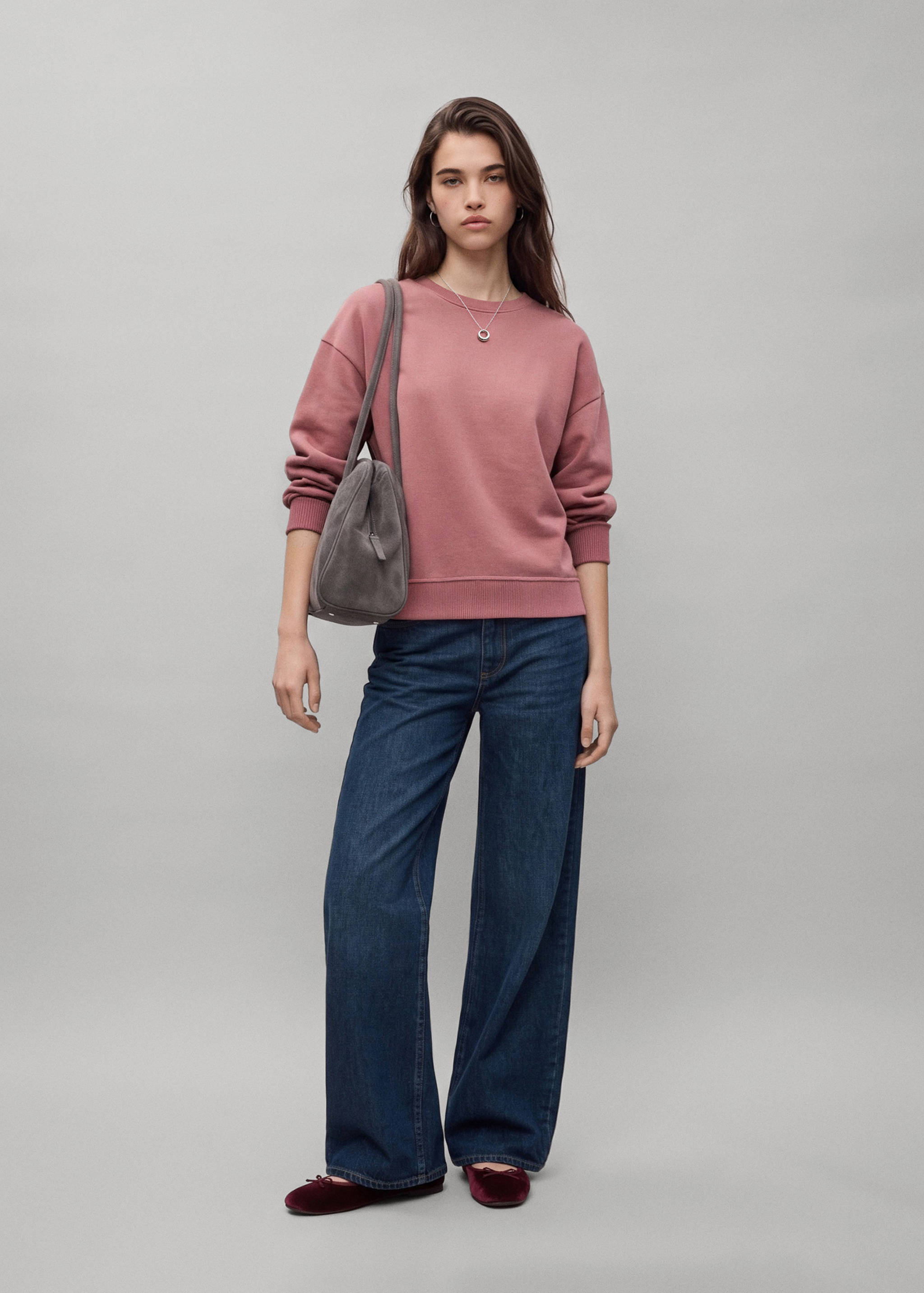 Sudadera rosa malva de cuello redondo combinada con vaqueros de pernera ancha.