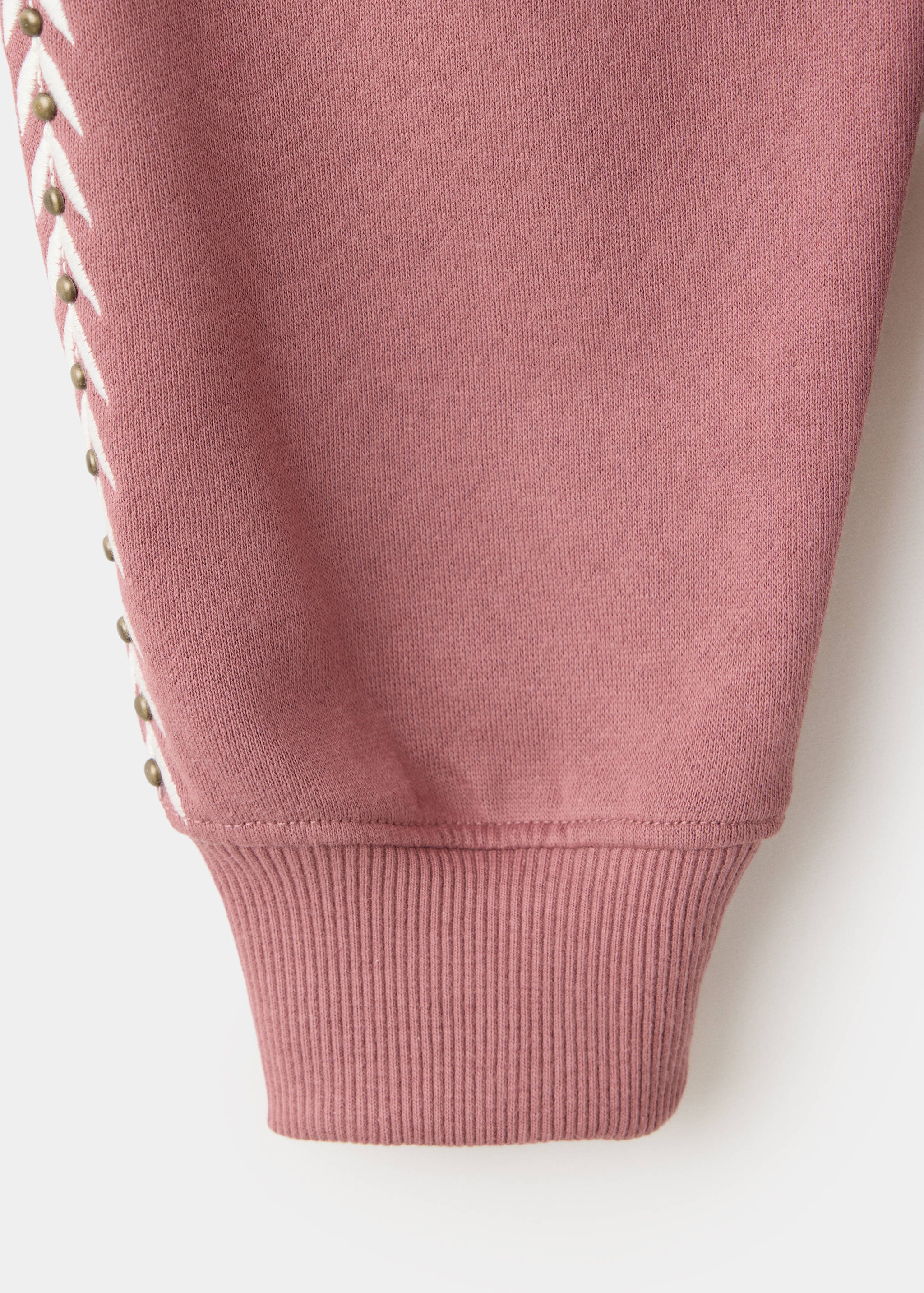 Detalle de tejido de sudadera en color malva con ribete lateral blanco de tachuelas.