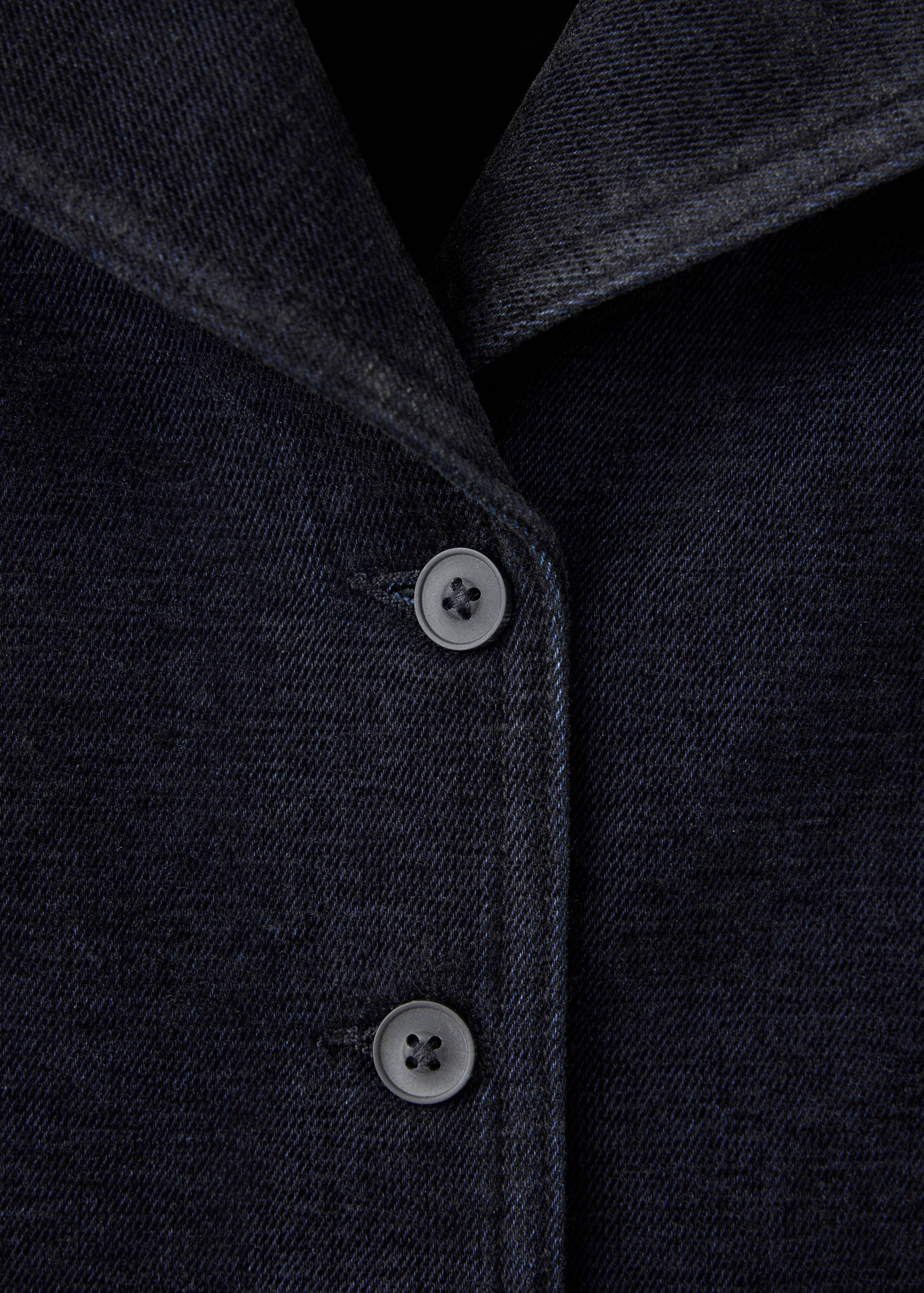 Close-up of a dark navy denim jacket showing the collar and button placket.