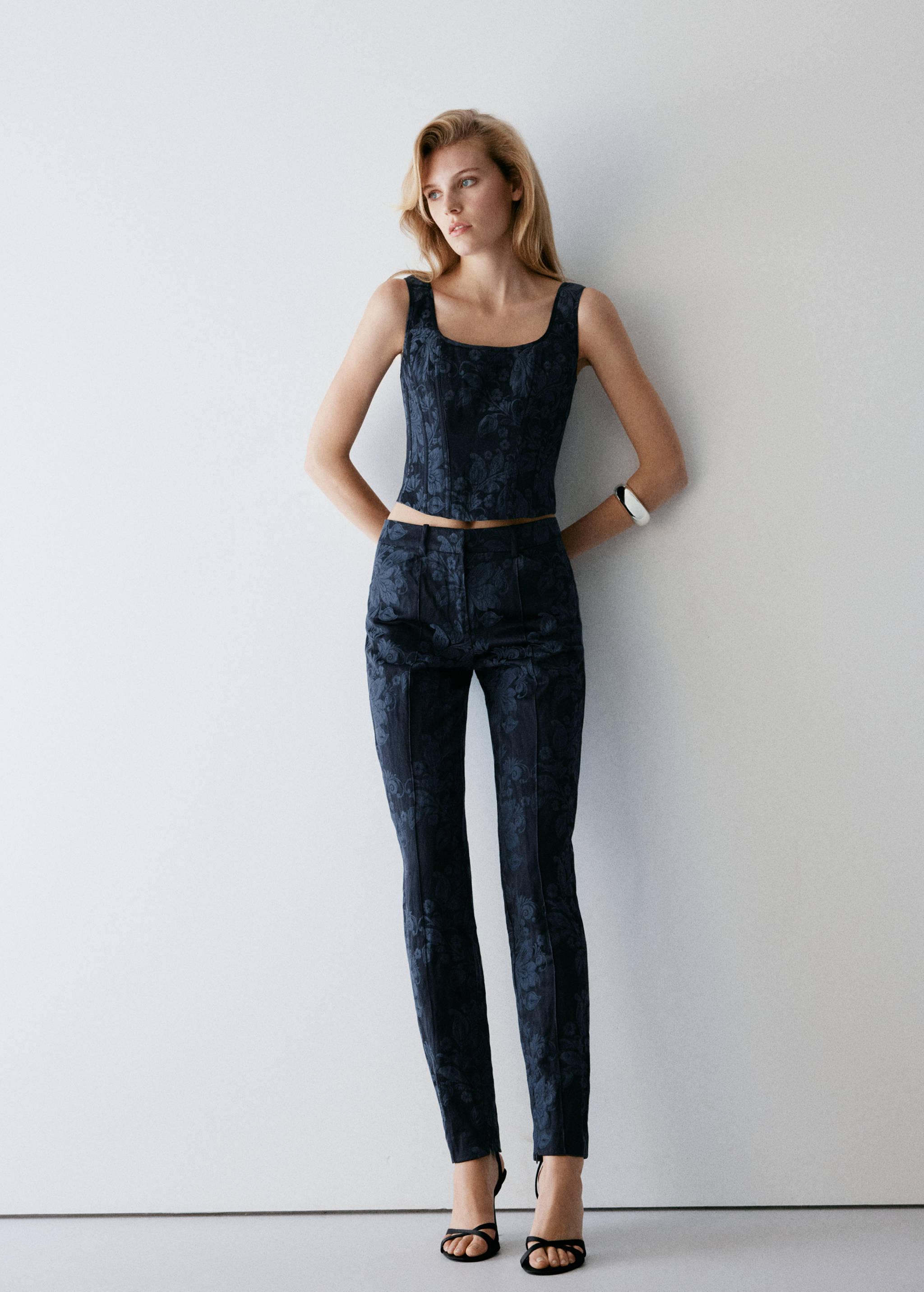 Navy blue floral jacquard trousers with a slim fit and tonal pattern, worn with a matching top.