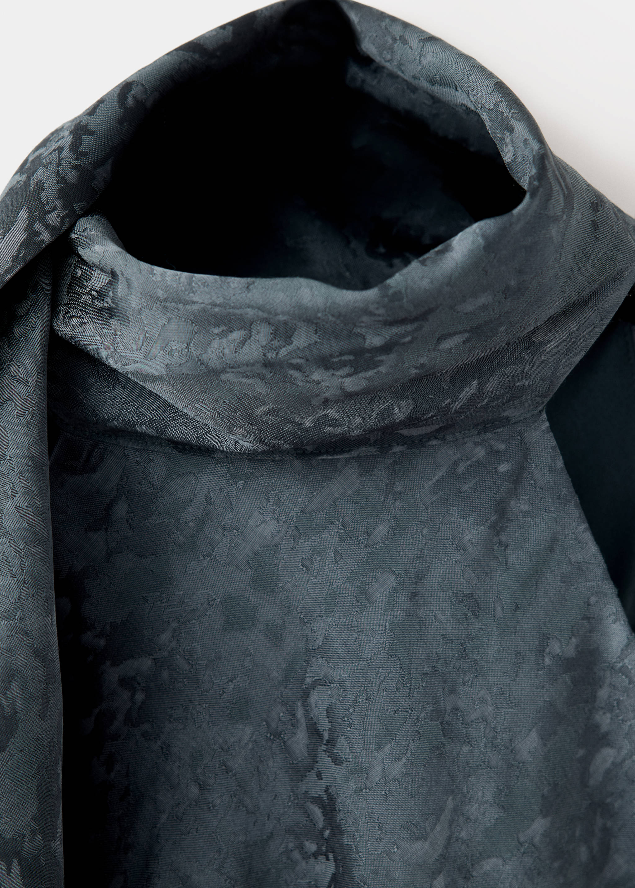 Dark grey patterned dress detail focusing on the high neckline.