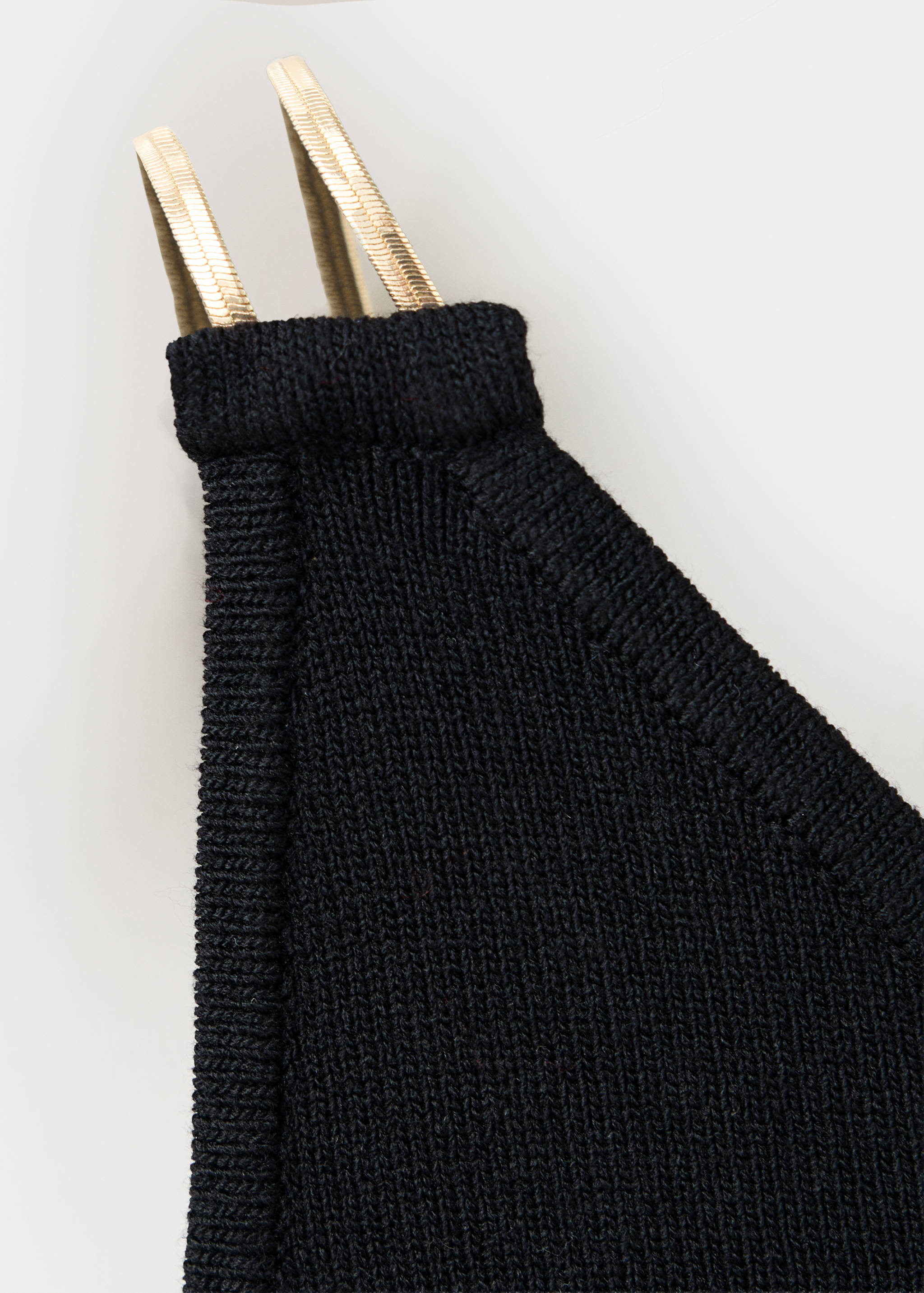 Close-up of a black knit top with gold-toned metallic straps.