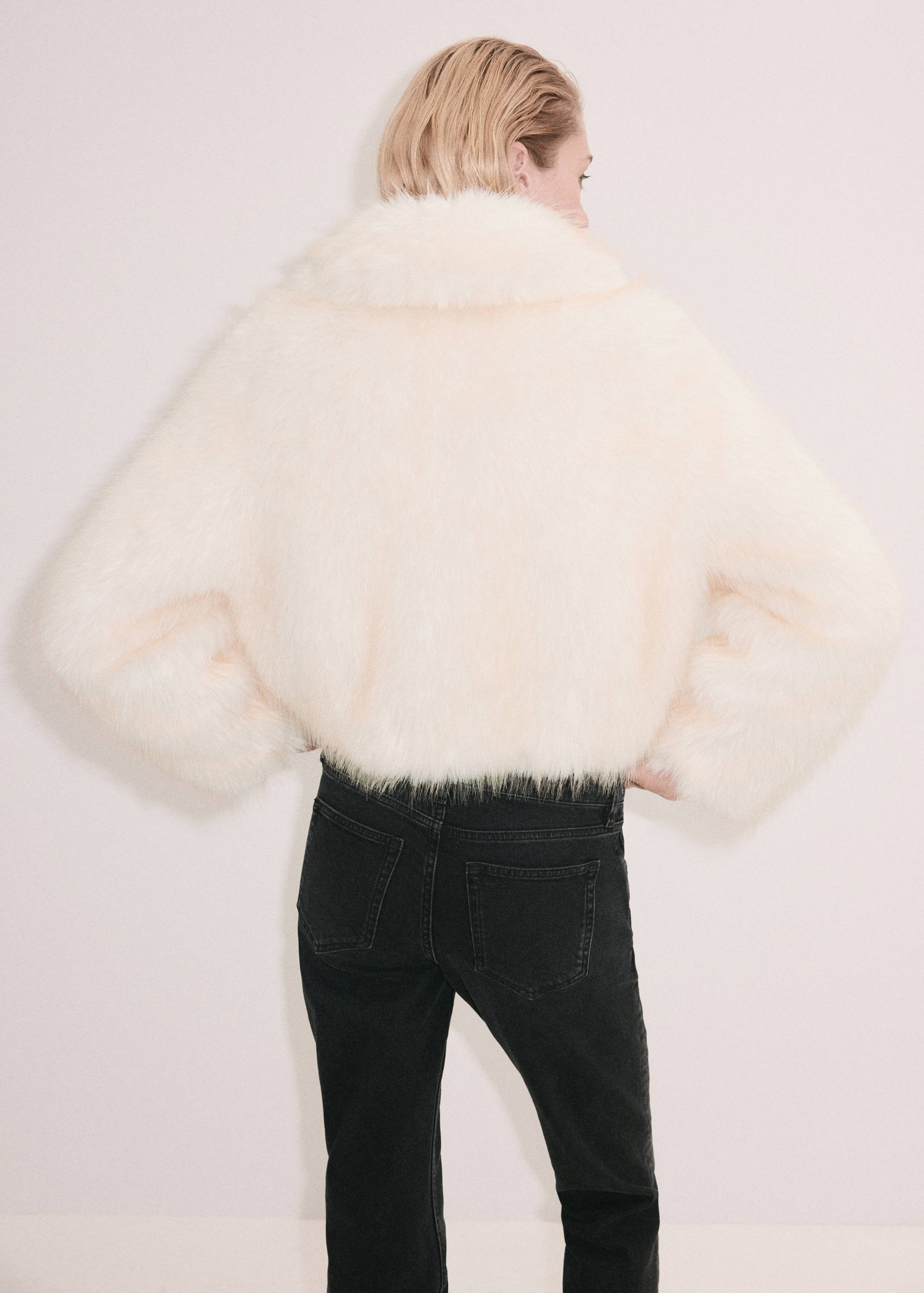 Cream-coloured faux-fur jacket shown from the back, paired with trousers.