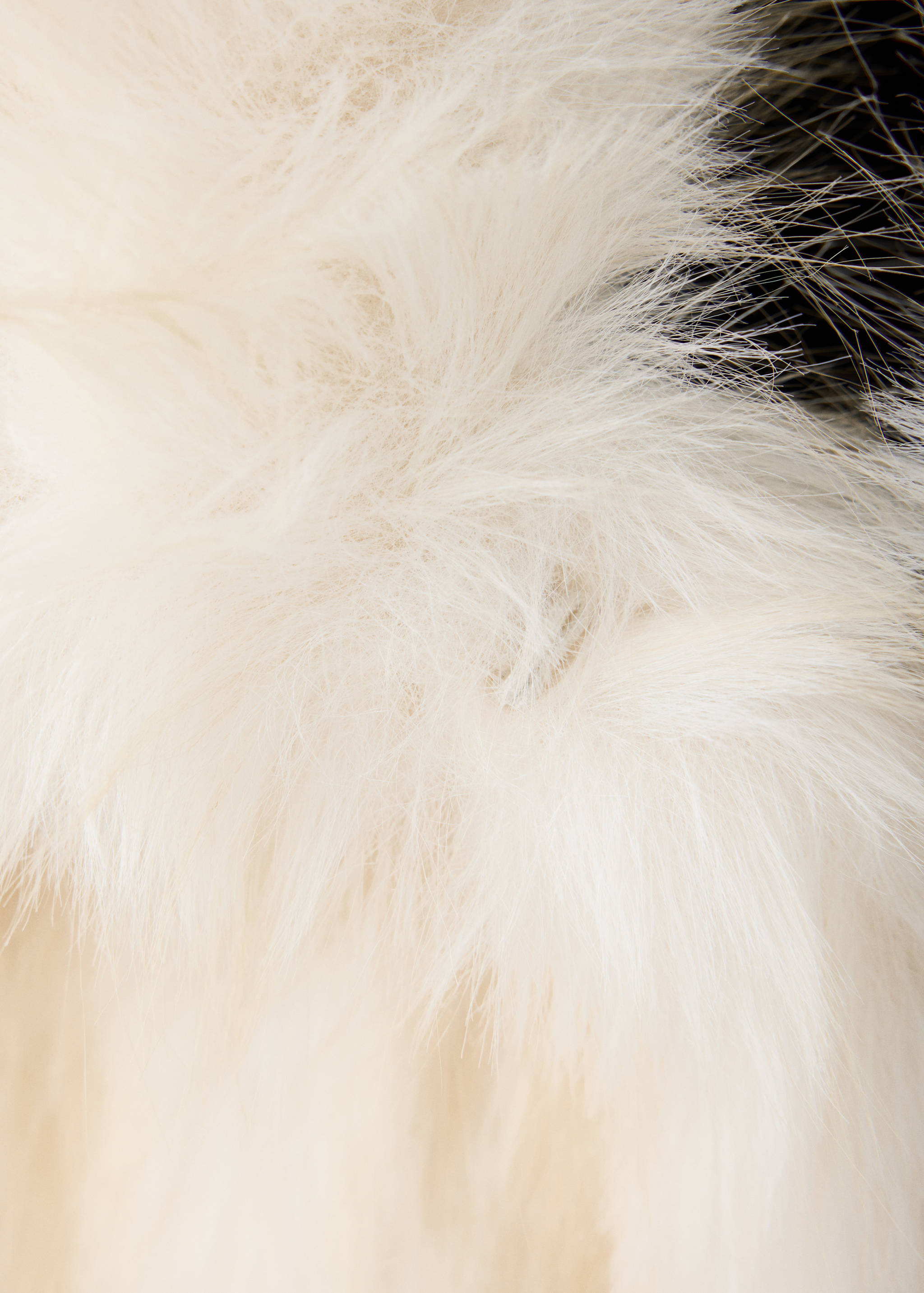 Close-up of white and cream faux-fur jacket fabric texture.