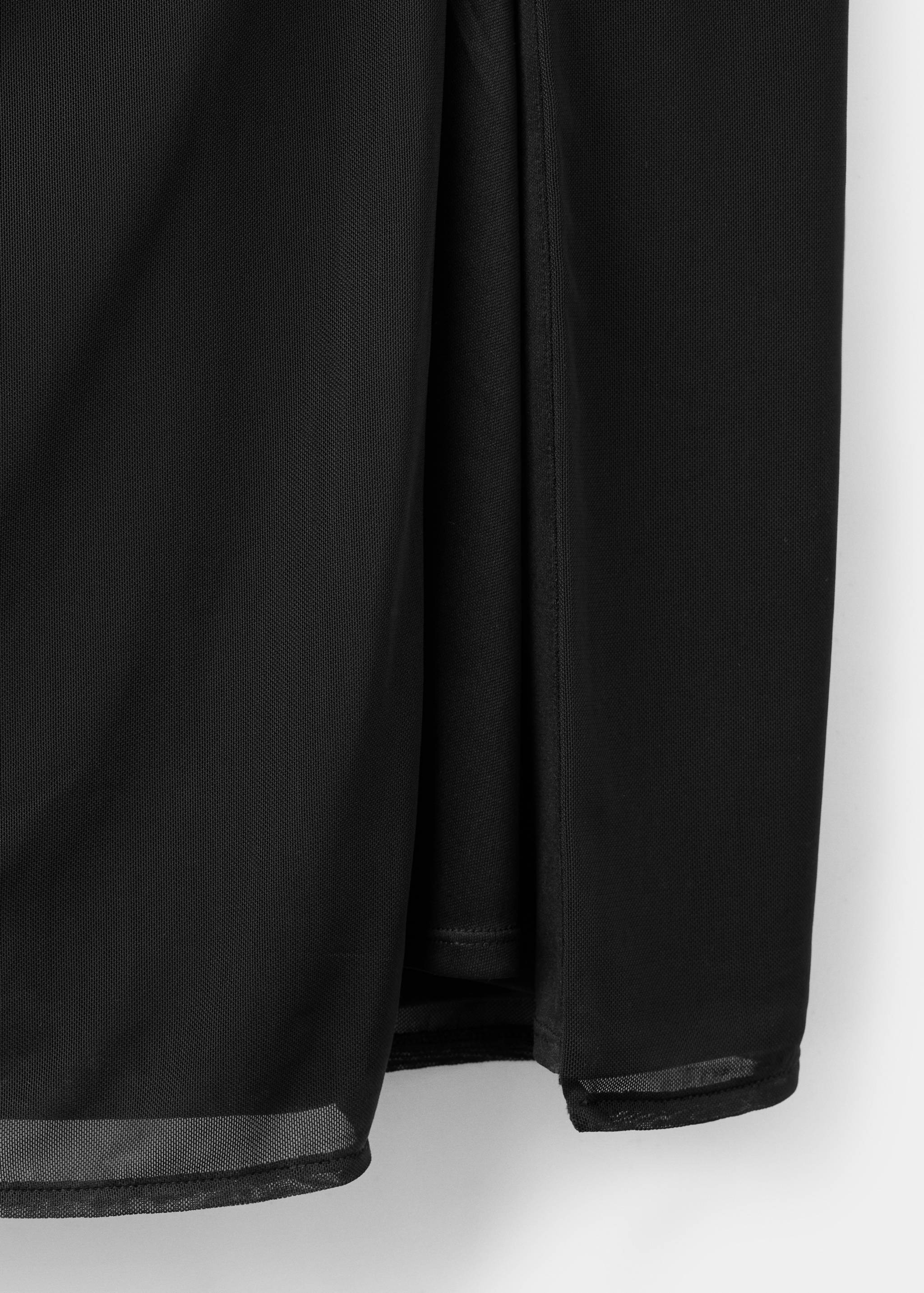 Close-up of a black mesh dress showing the layered hem and slit.