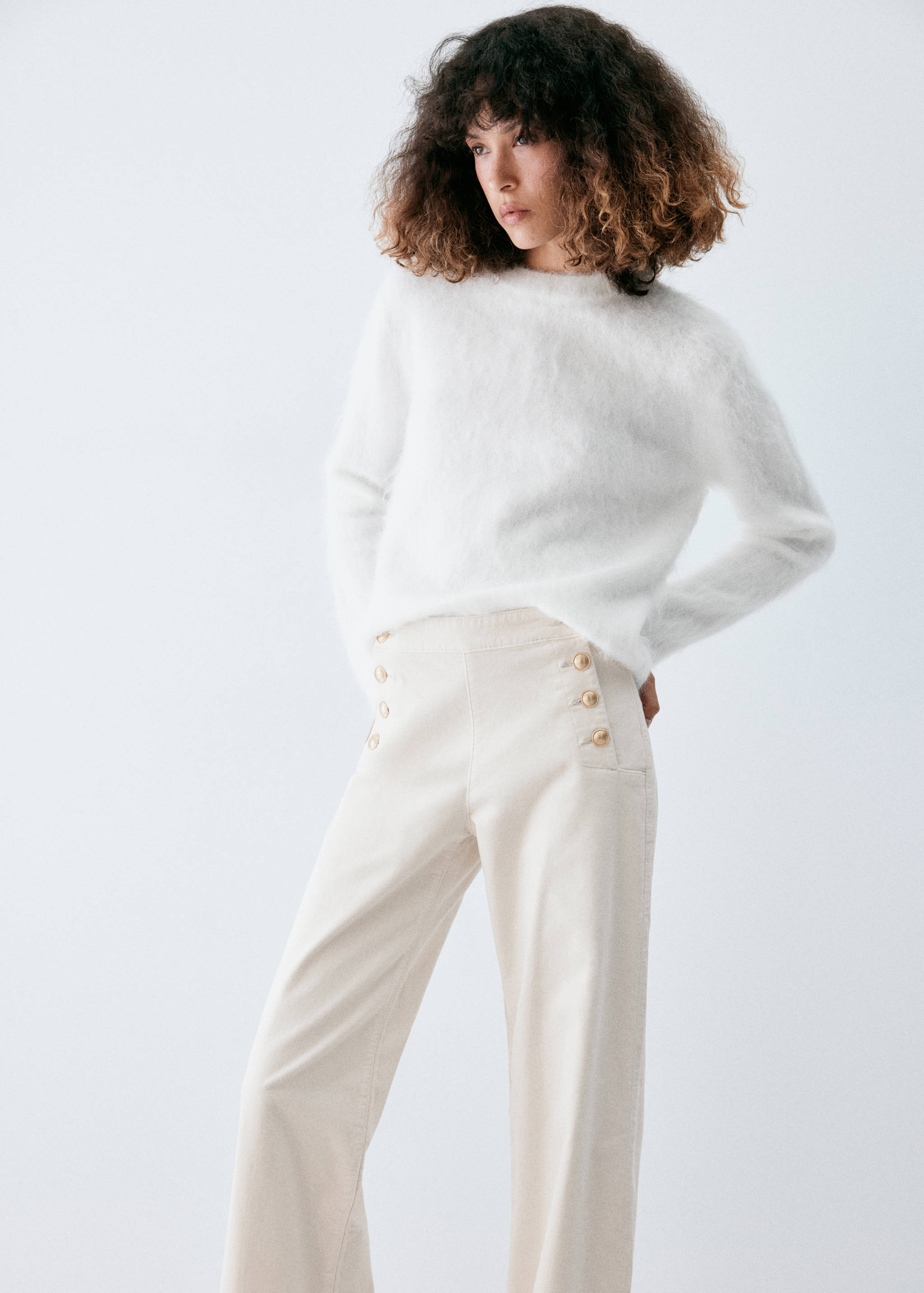Cream denim trousers with high waist and gold buttons, worn with a white sweater.