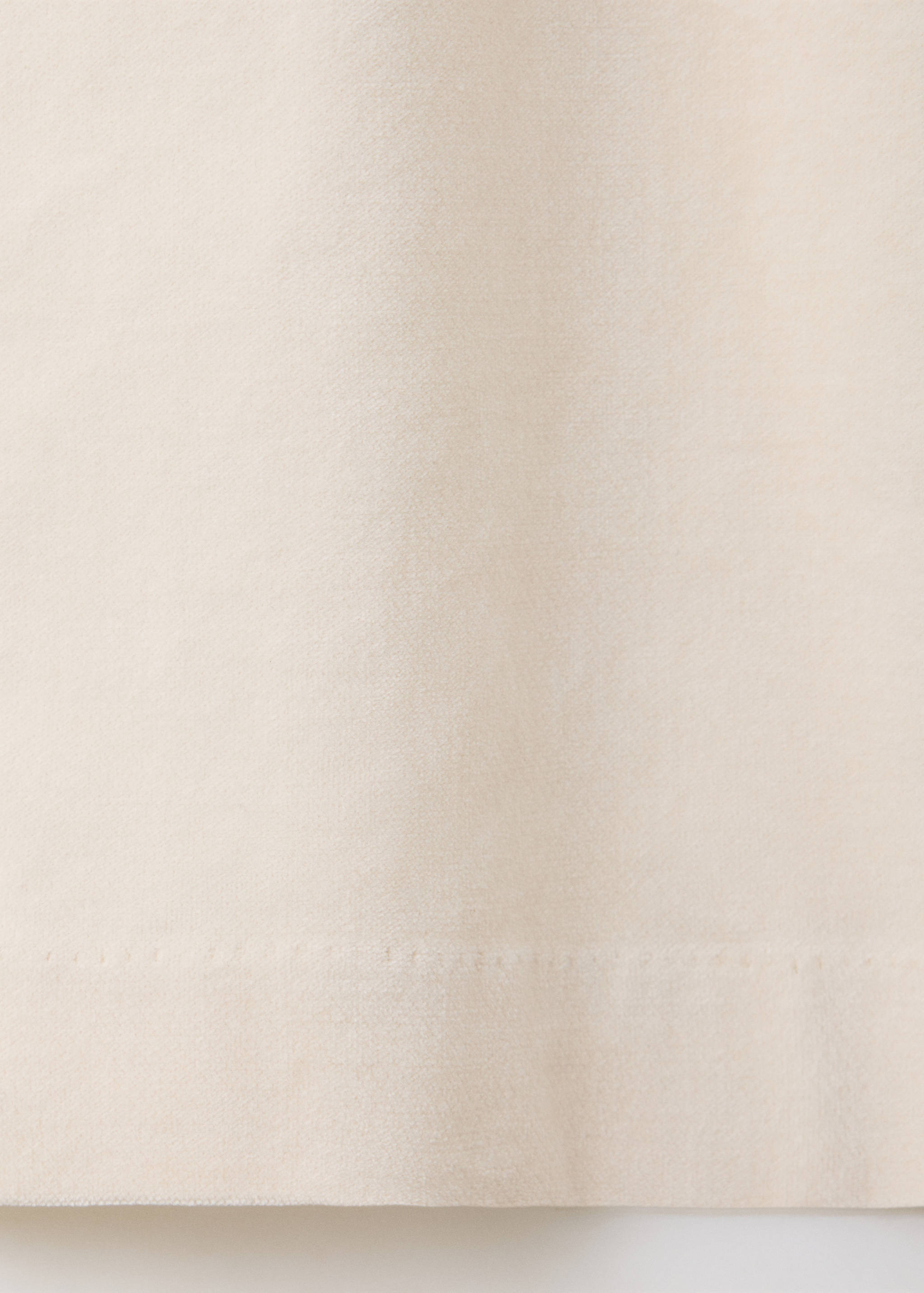 Close-up of the light beige denim fabric texture and hem detail.