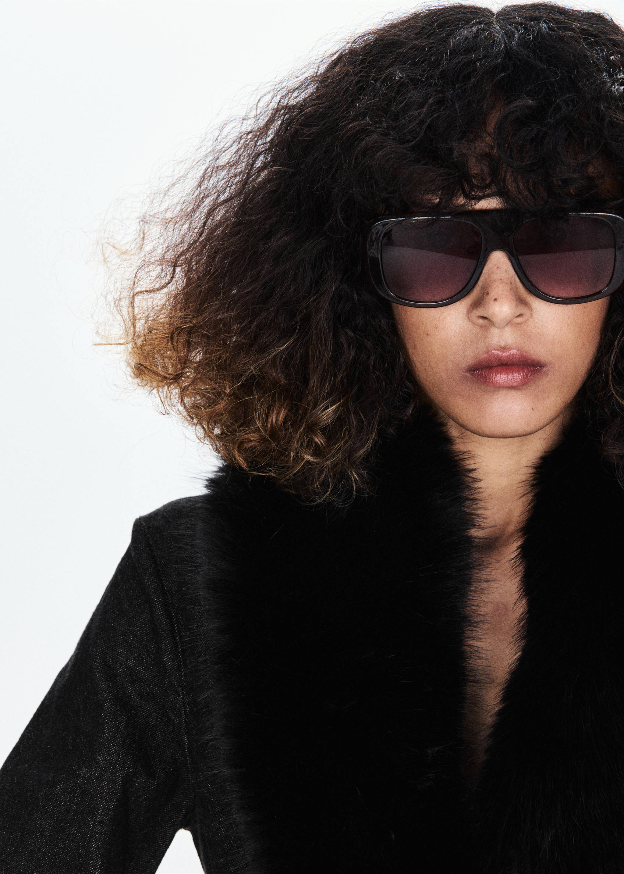 Close-up of a black blazer with a faux-fur collar, worn with sunglasses., Open Blue. Ref: 37089134-00.