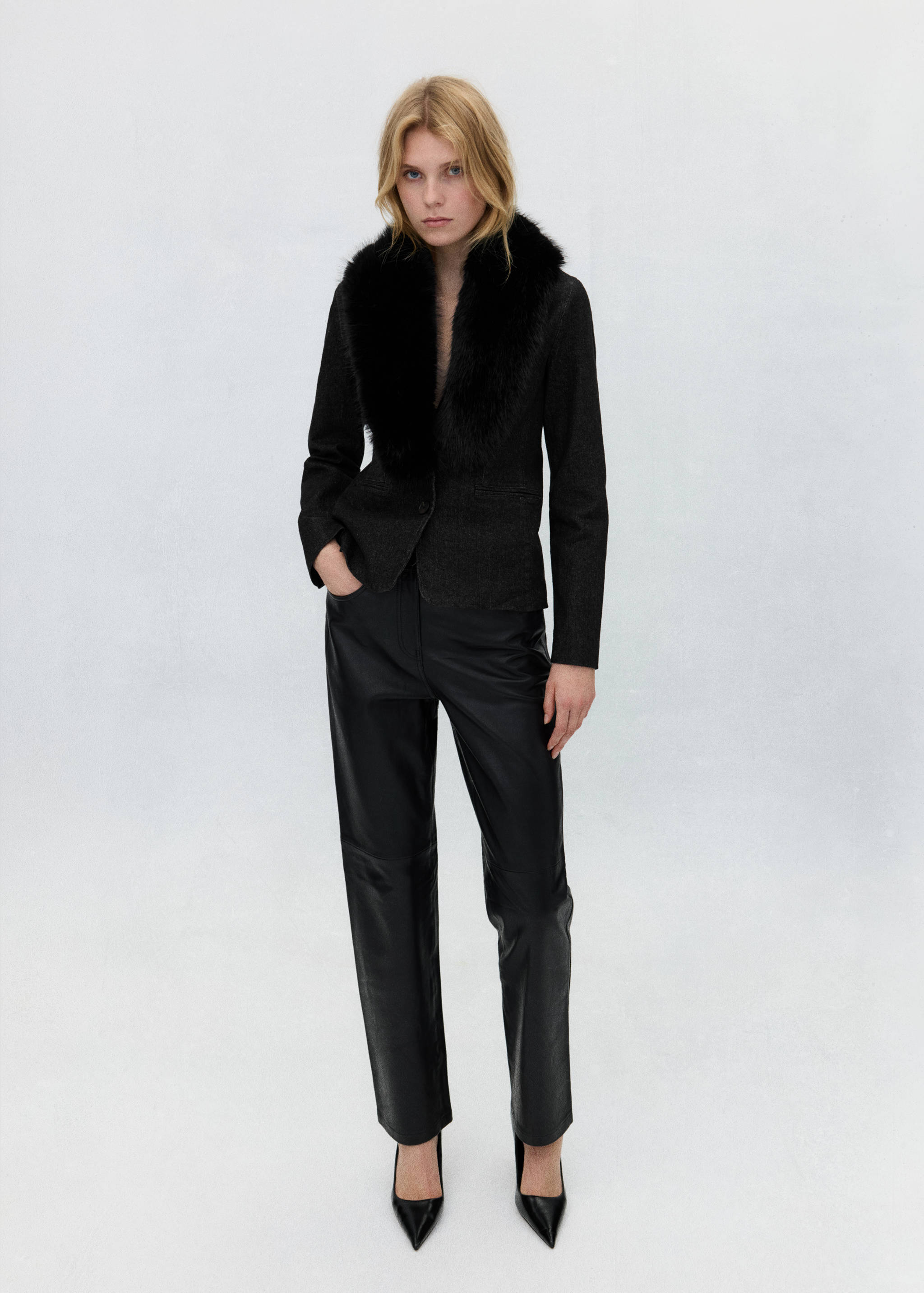 Dark blazer with black faux-fur collar, paired with black trousers.
