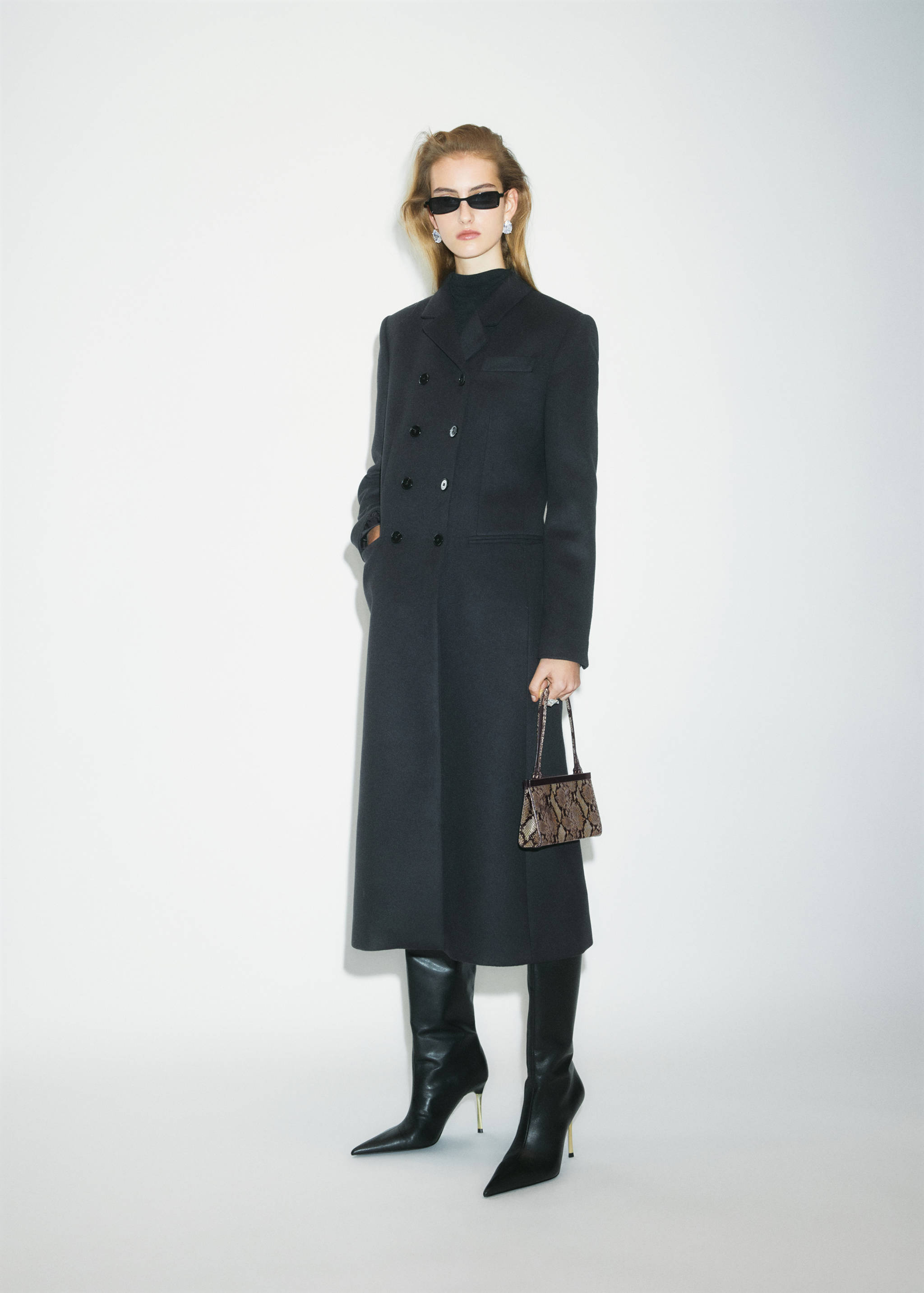 Black heeled boots with pointed toes worn with a long coat