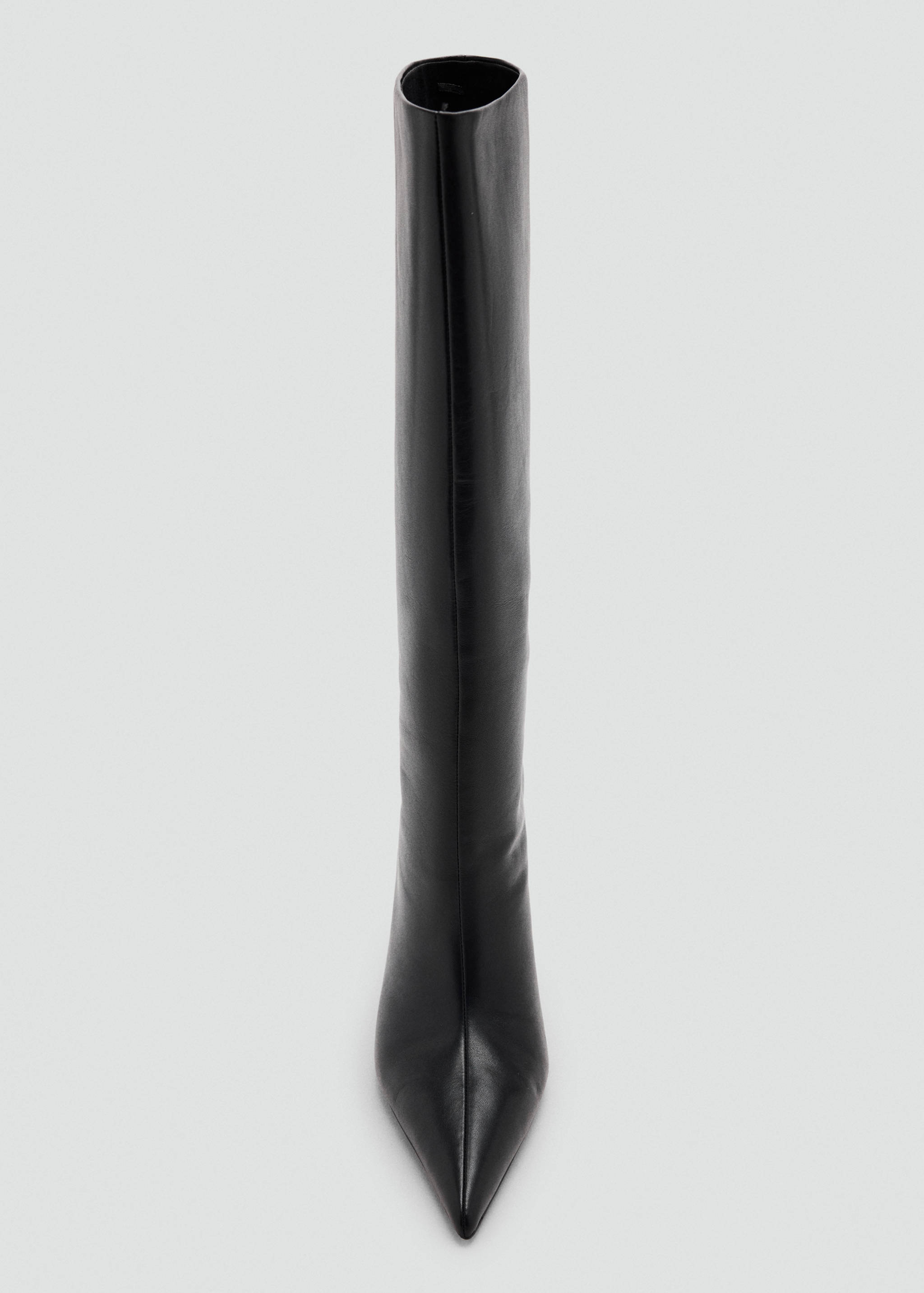 Close-up of a black leather boot featuring a pointed toe and a tall shaft.
