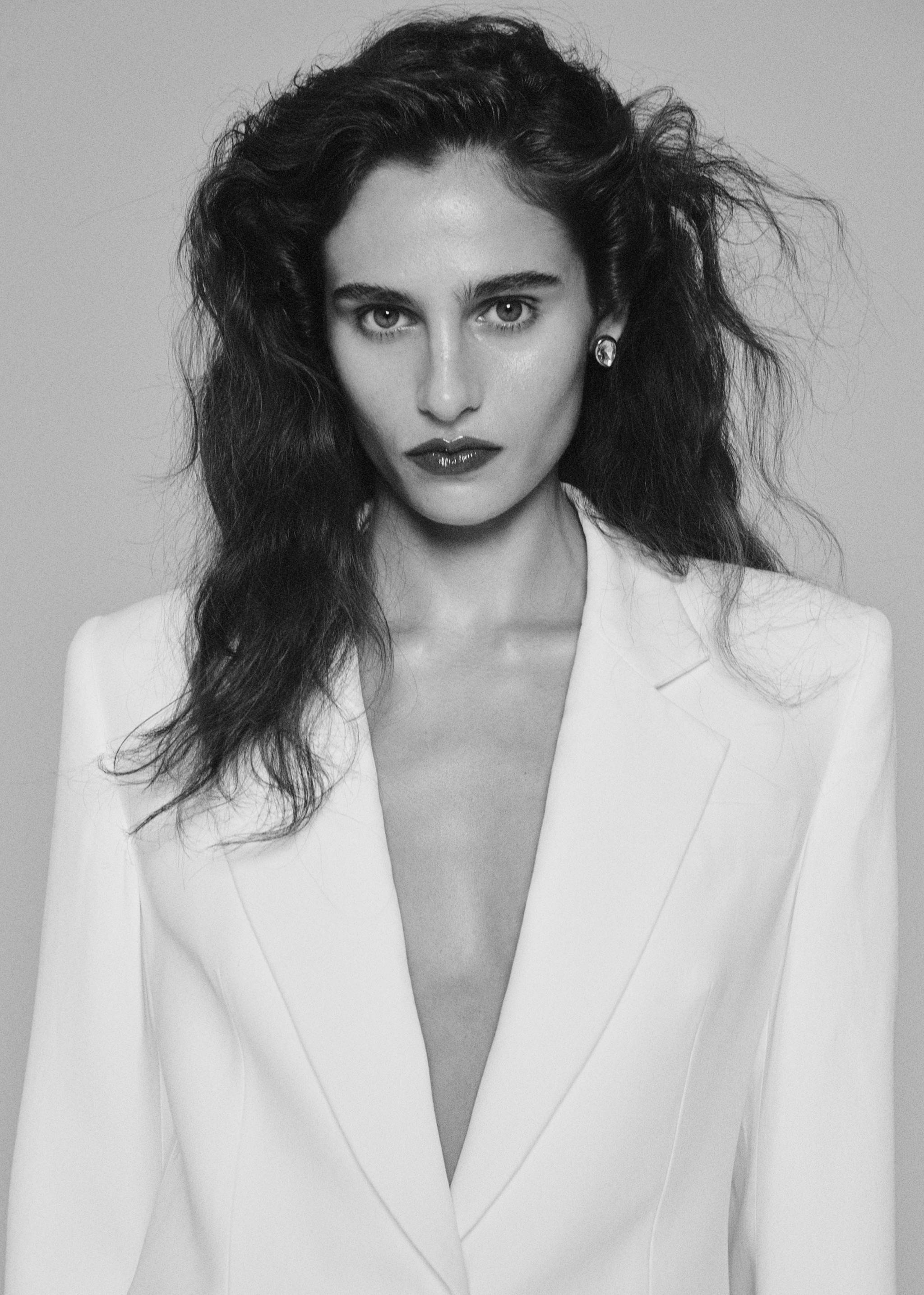 Close-up portrait of a model wearing a white dress with a deep V-neck.
