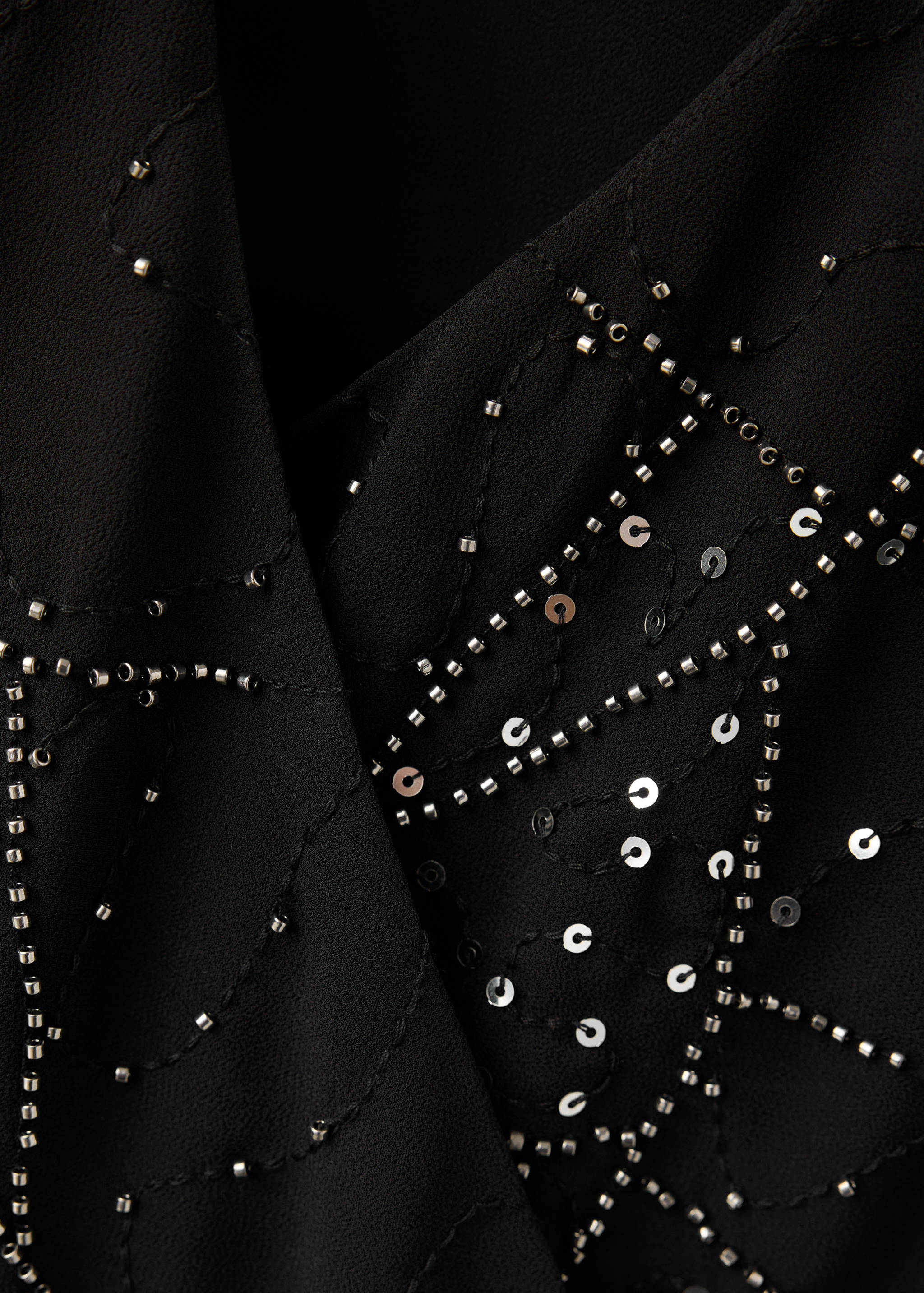 Close-up of a black beaded and sequinned top with a v-neck.