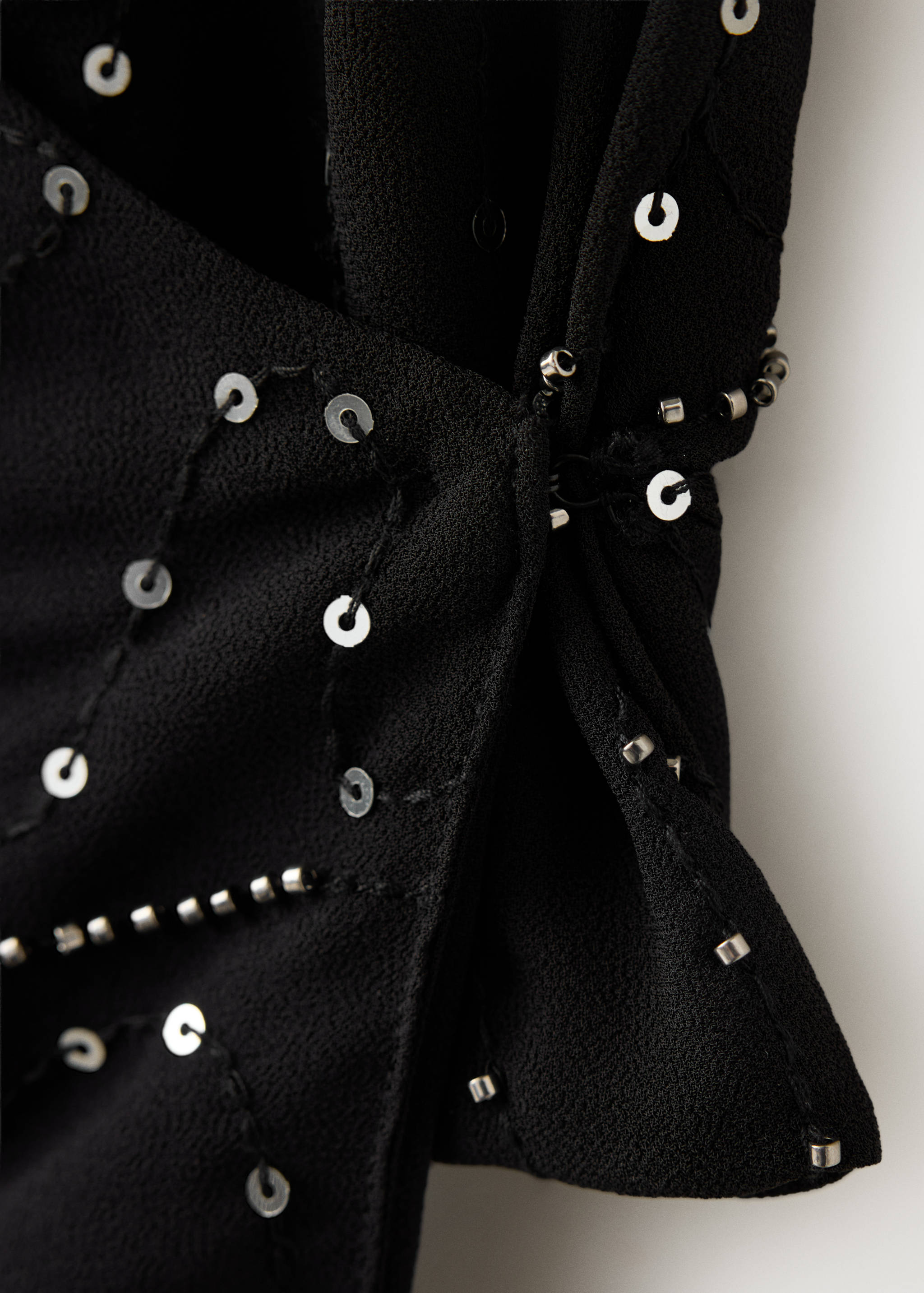 Close-up of a black top with silver sequin and bead embellishments.