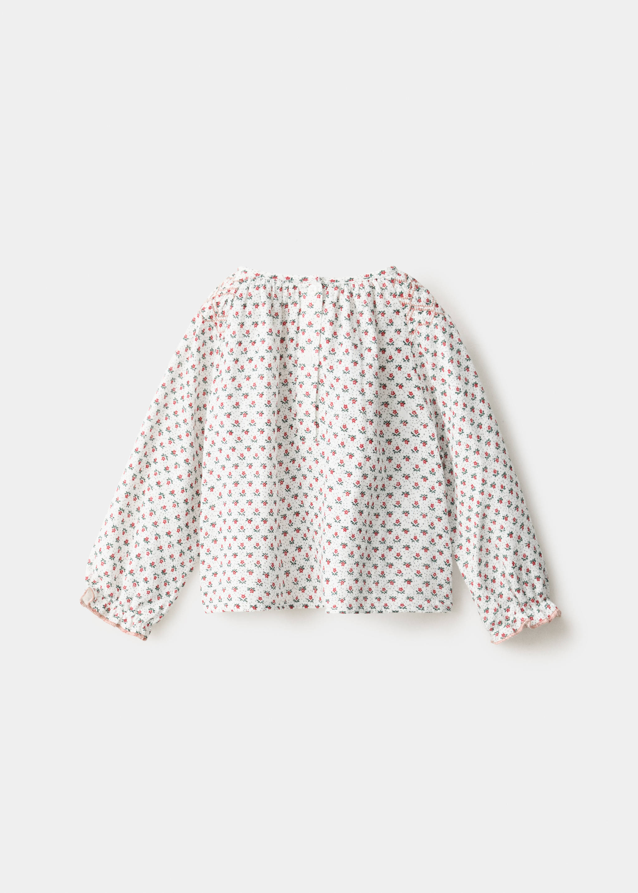 Back of a floral print kids' blouse with smocked shoulders and ruffled cuffs.