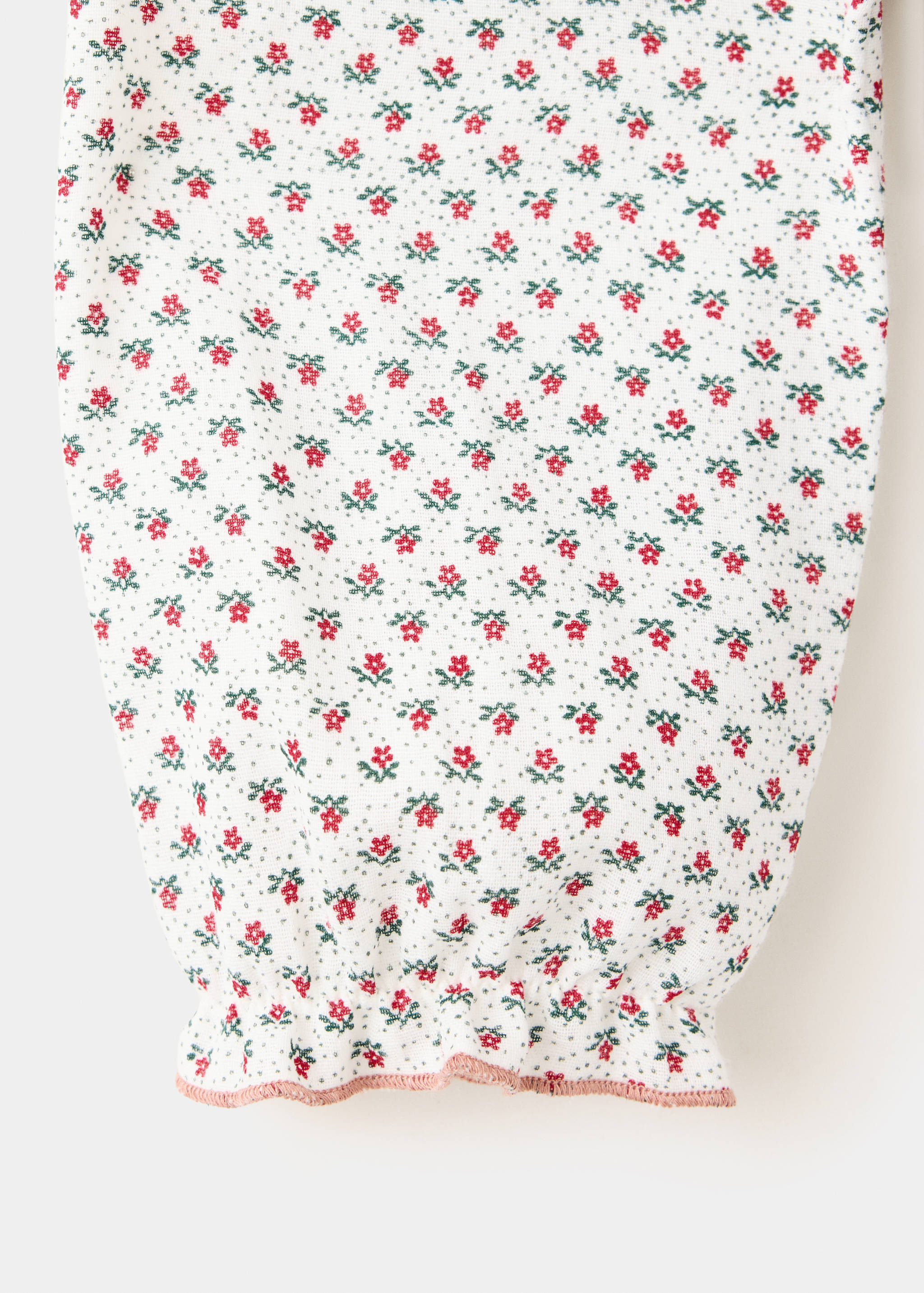 Close-up of a white floral blouse sleeve with a gathered cuff and pink trim.