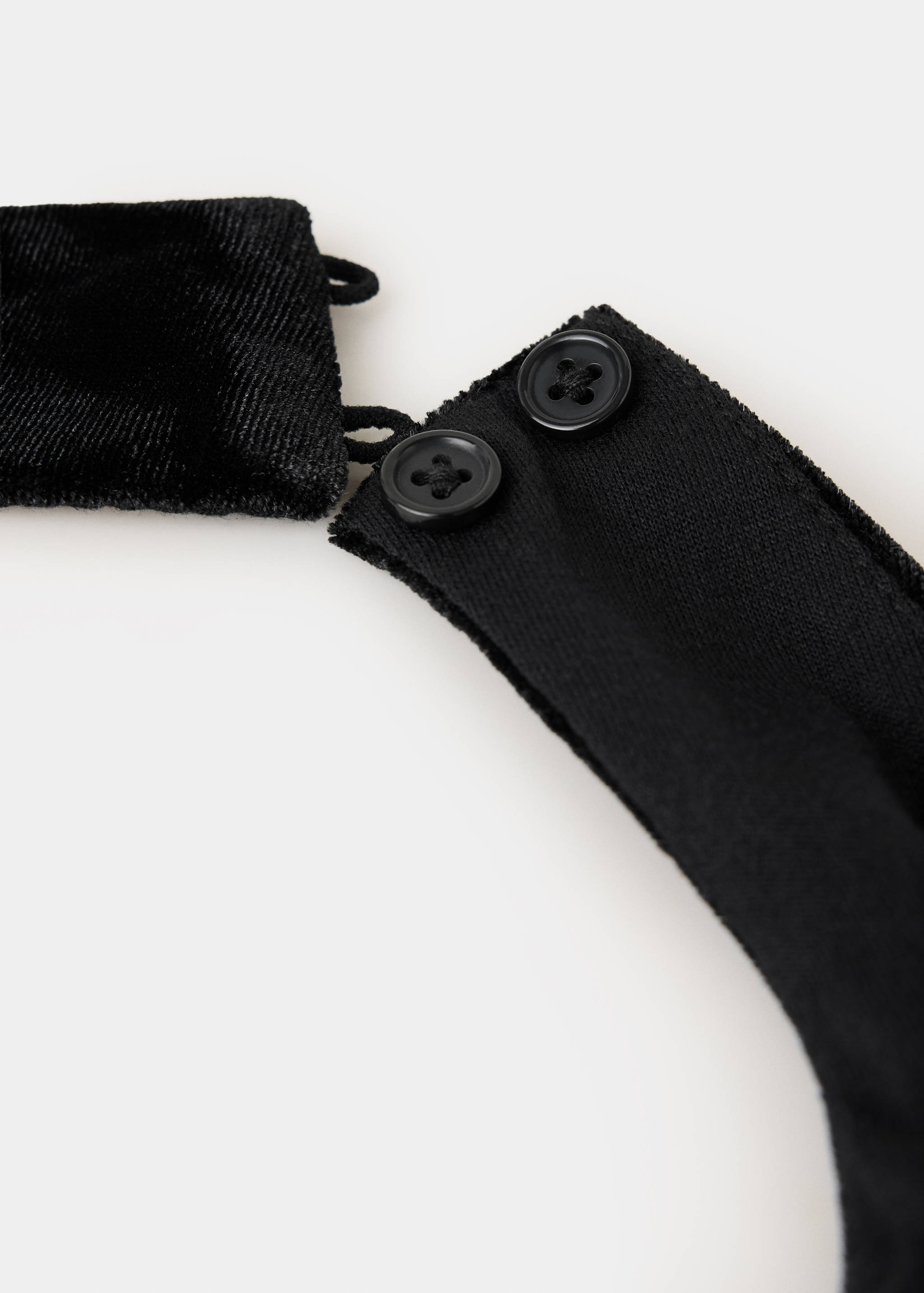 Close-up of a black top showing button closure and fabric detail.