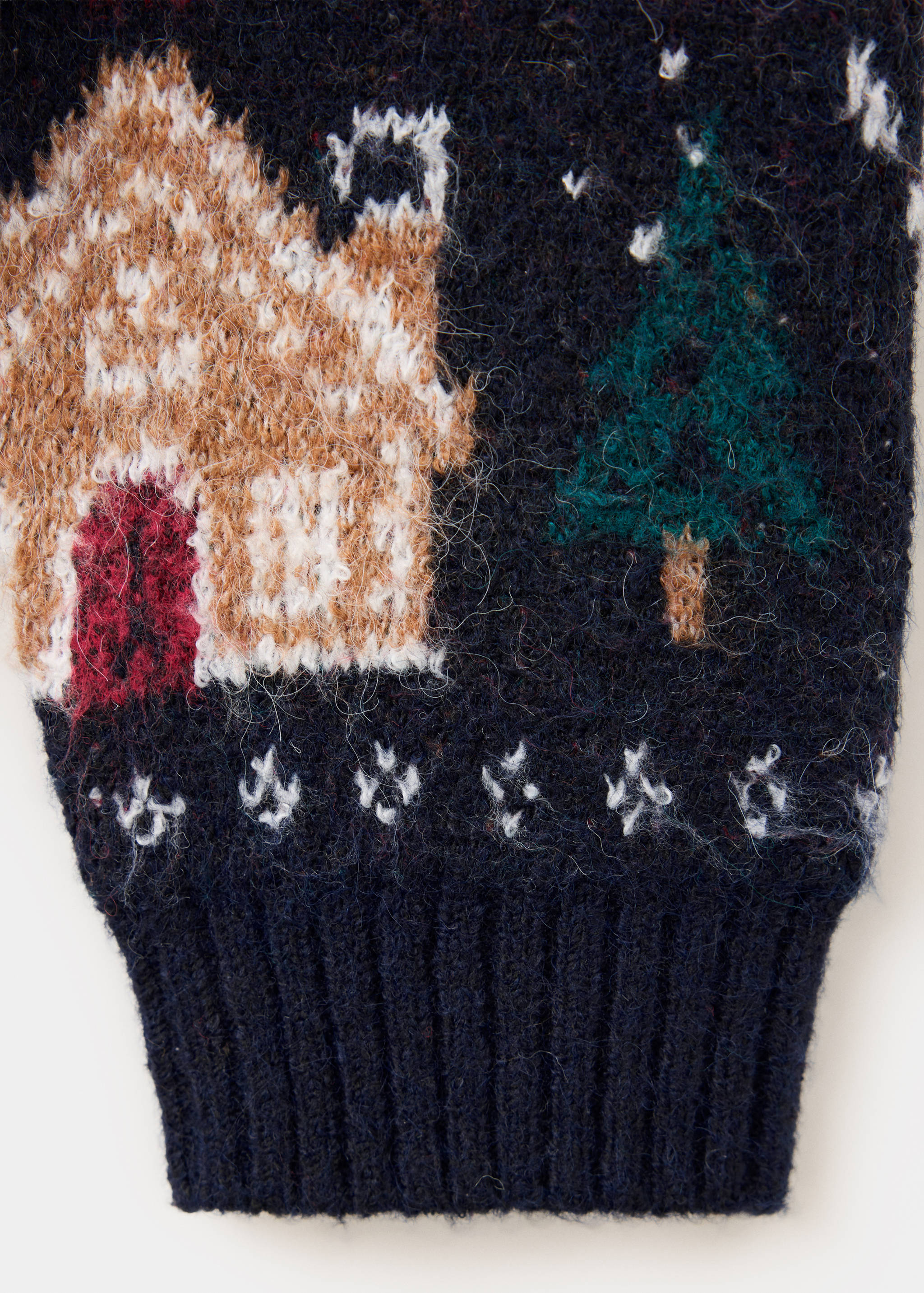 Close-up of a navy blue jersey fabric featuring a festive knit house and tree pattern with a ribbed hem.