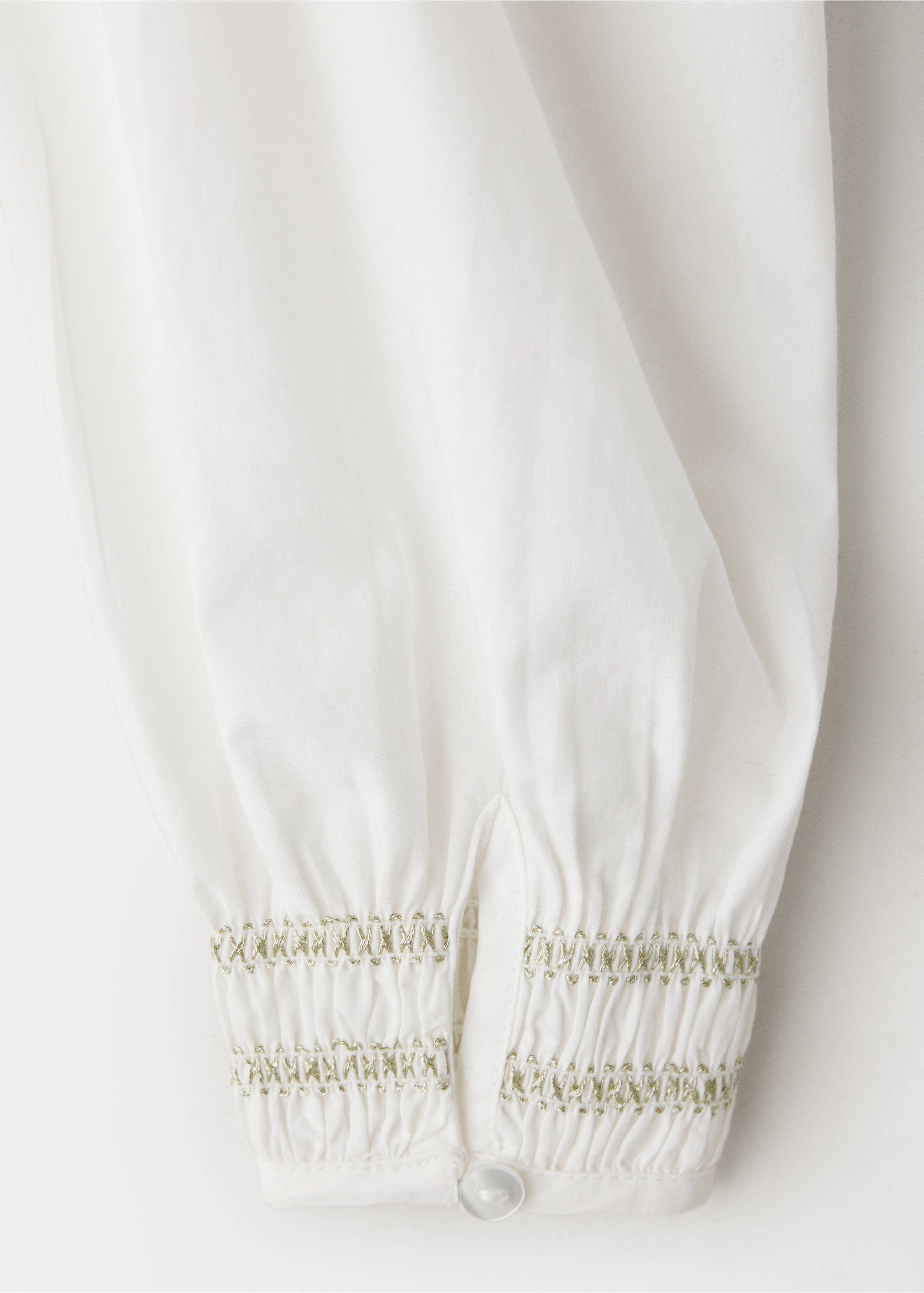 Primer plano de la manga de una blusa blanca que muestra el detalle del puño bordado., Blanco. Ref: 37089225-00.