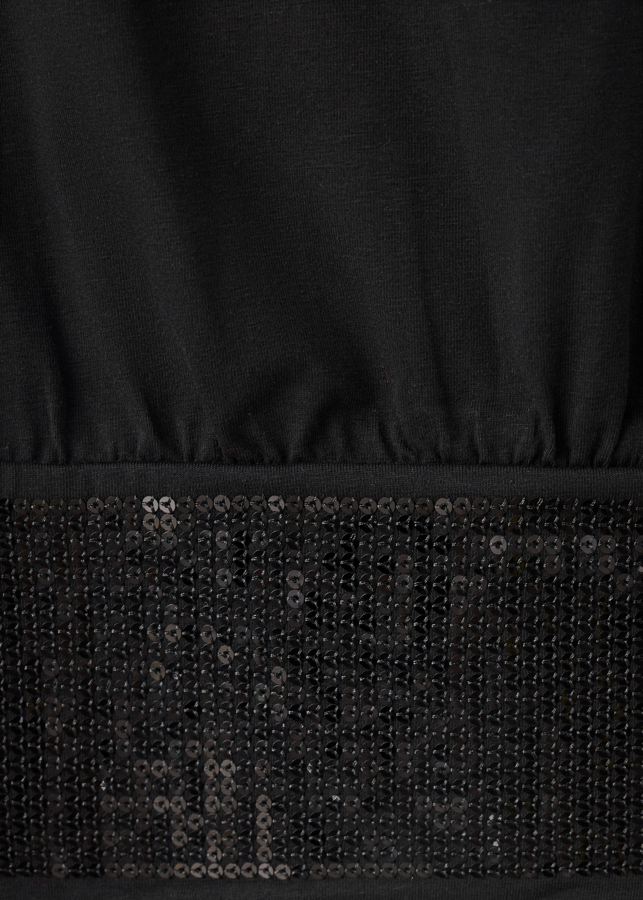 Close-up of a black t-shirt with a sequin hem.