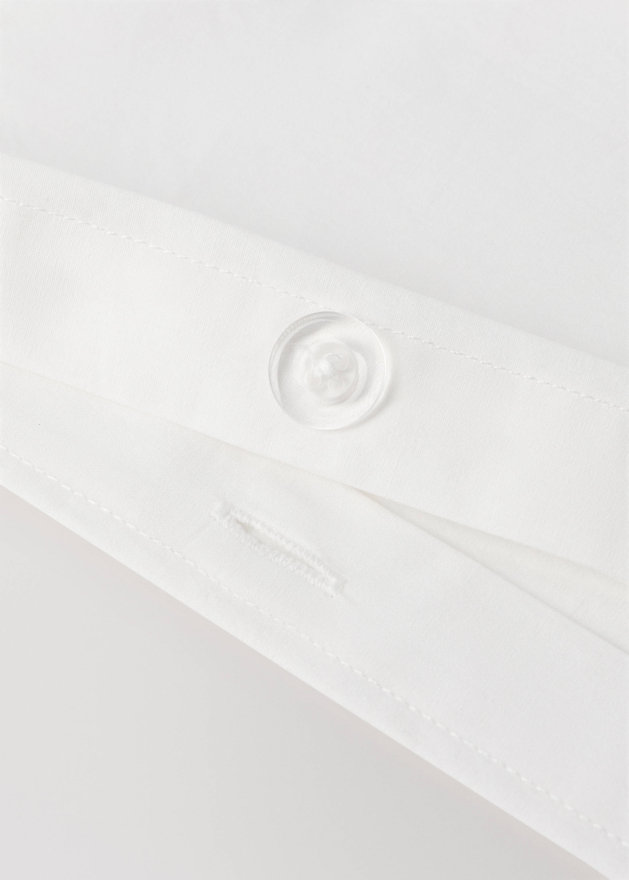 White cot duvet cover detail showing a button closure.