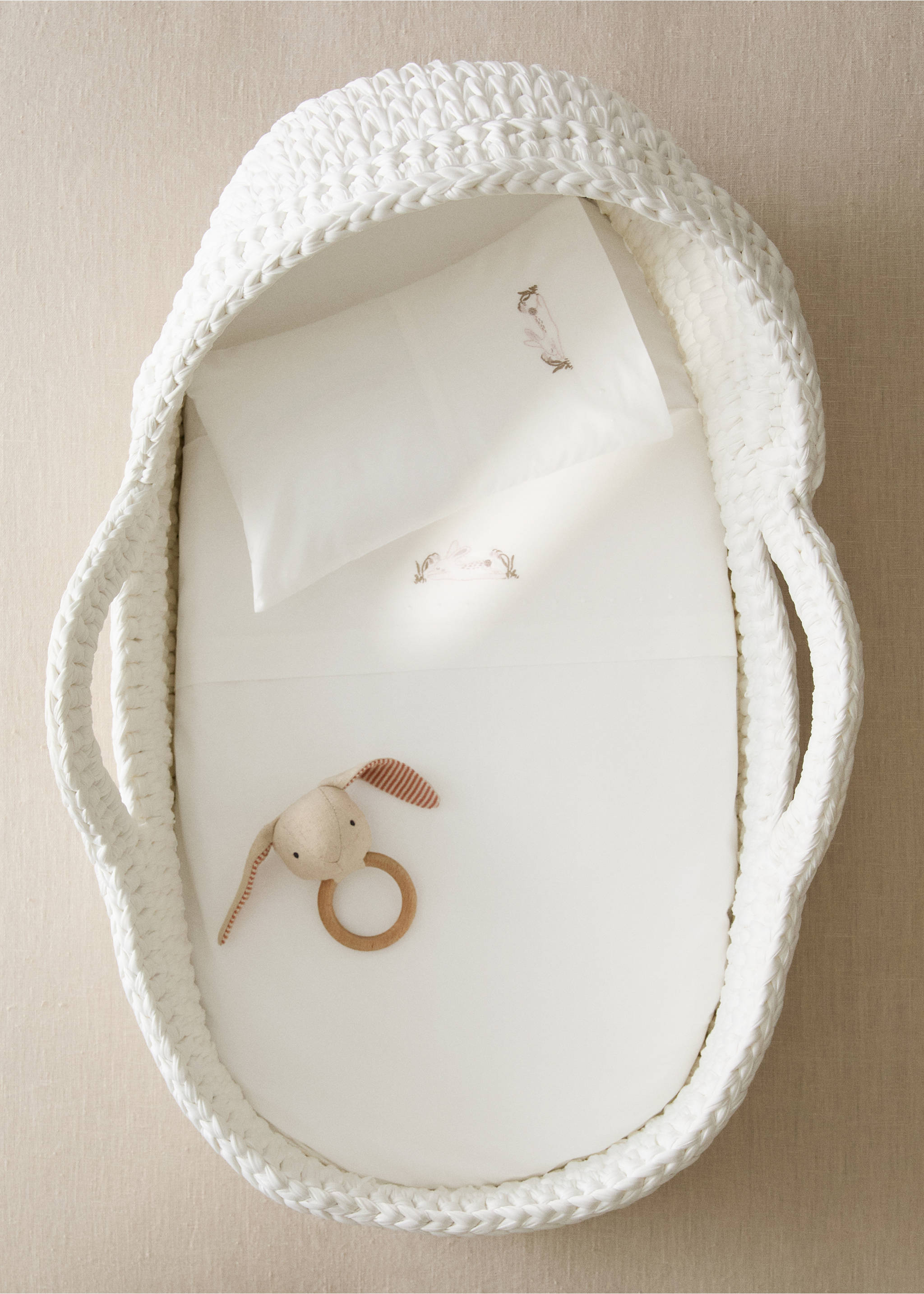 White knitted bassinet with a matching embroidered bed linen set and a rabbit rattle., Medium Brown. Ref: 37092559-00.