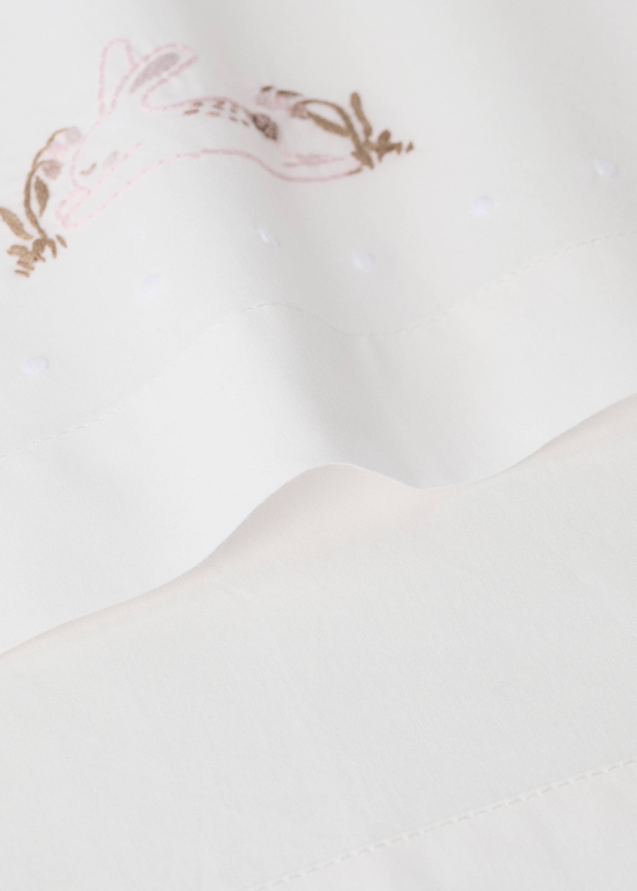 White bedding set with an embroidered rabbit and floral motif detail.