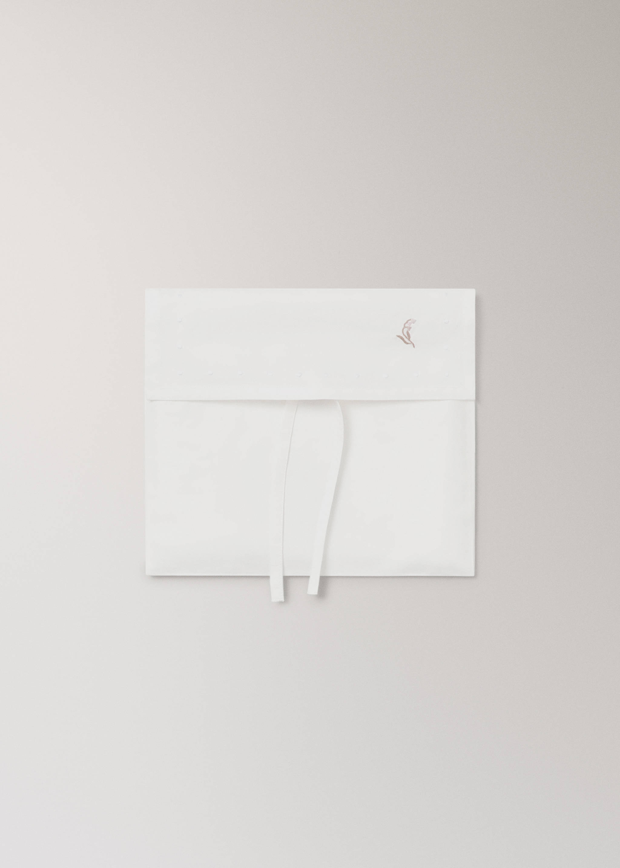 White bedding set piece with delicate embroidery and ties.