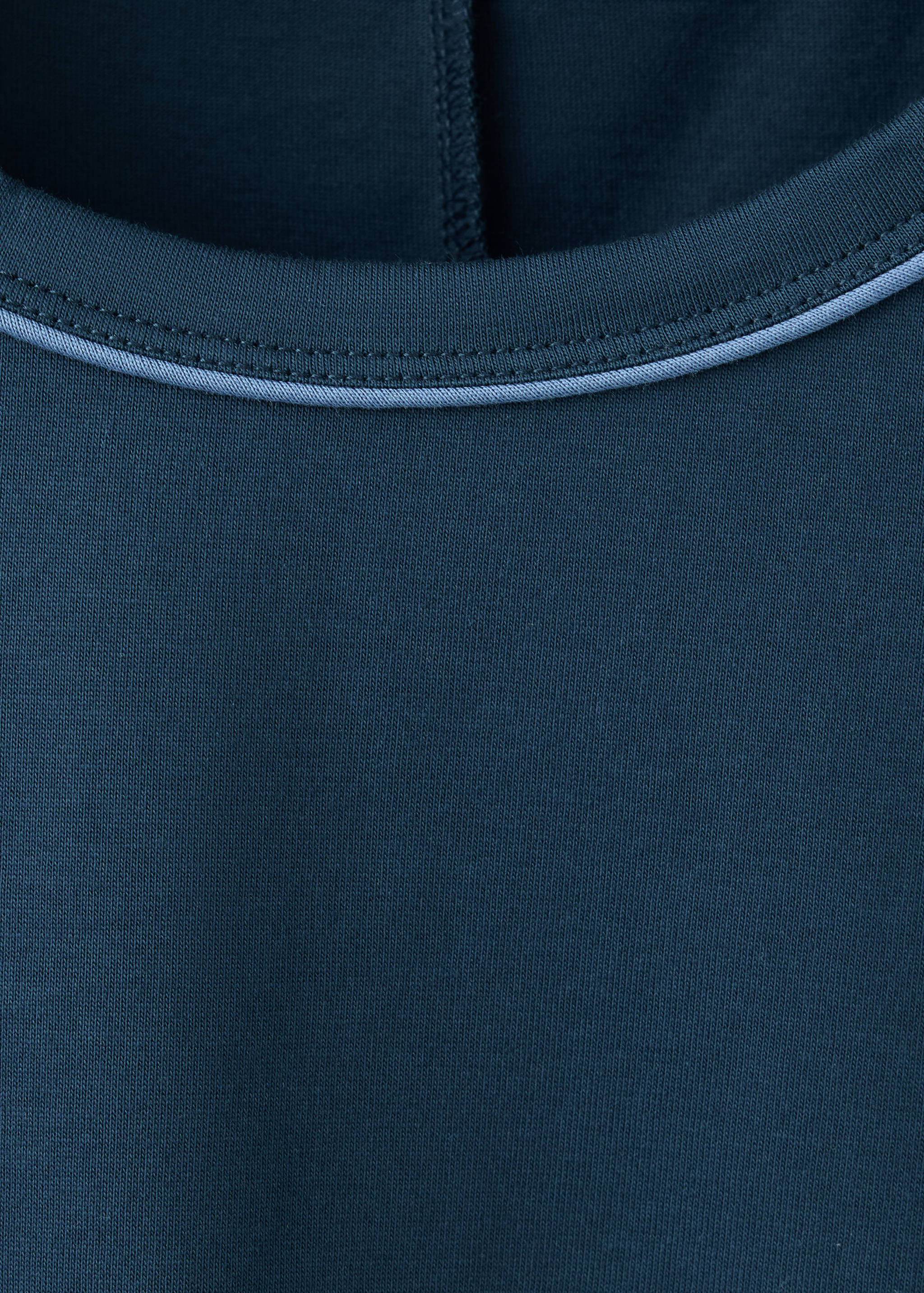 Detalle de escote de camiseta de pijama azul oscuro con ribete en azul claro.