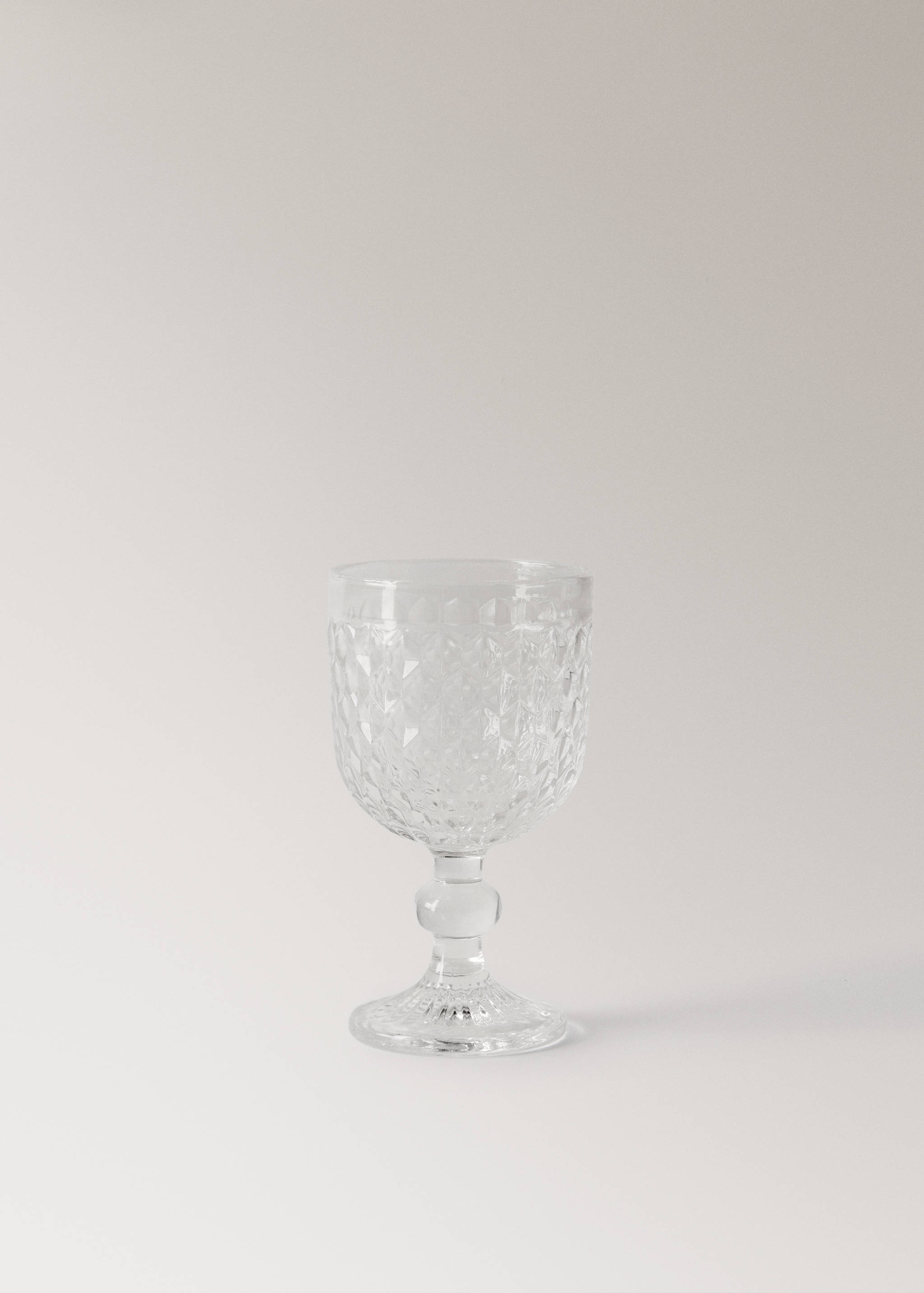 Clear glass goblet with a textured diamond-cut pattern and a short stem.