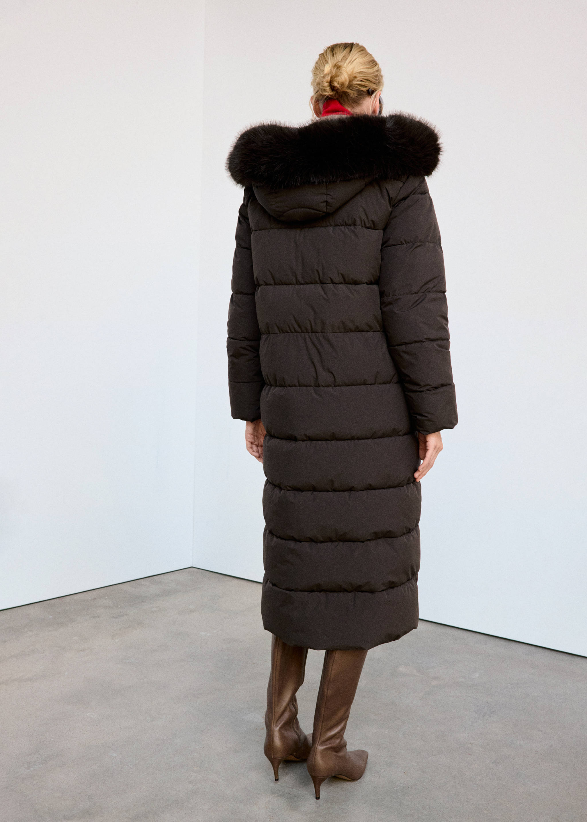 Back view of a long dark brown quilted anorak with a faux-fur trimmed hood.