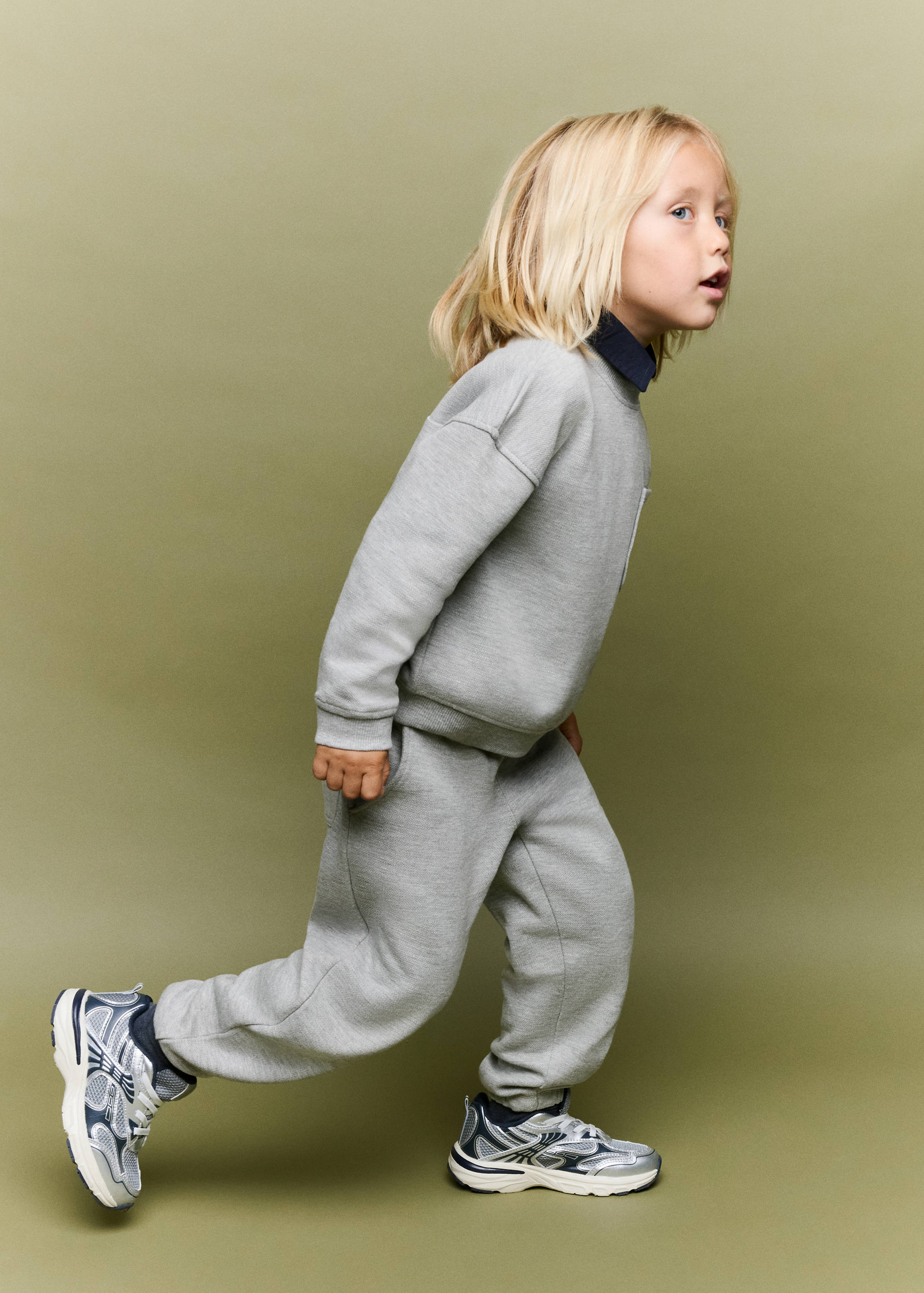 Grey joggers for kids with elasticated cuffs, worn as a matching set.
