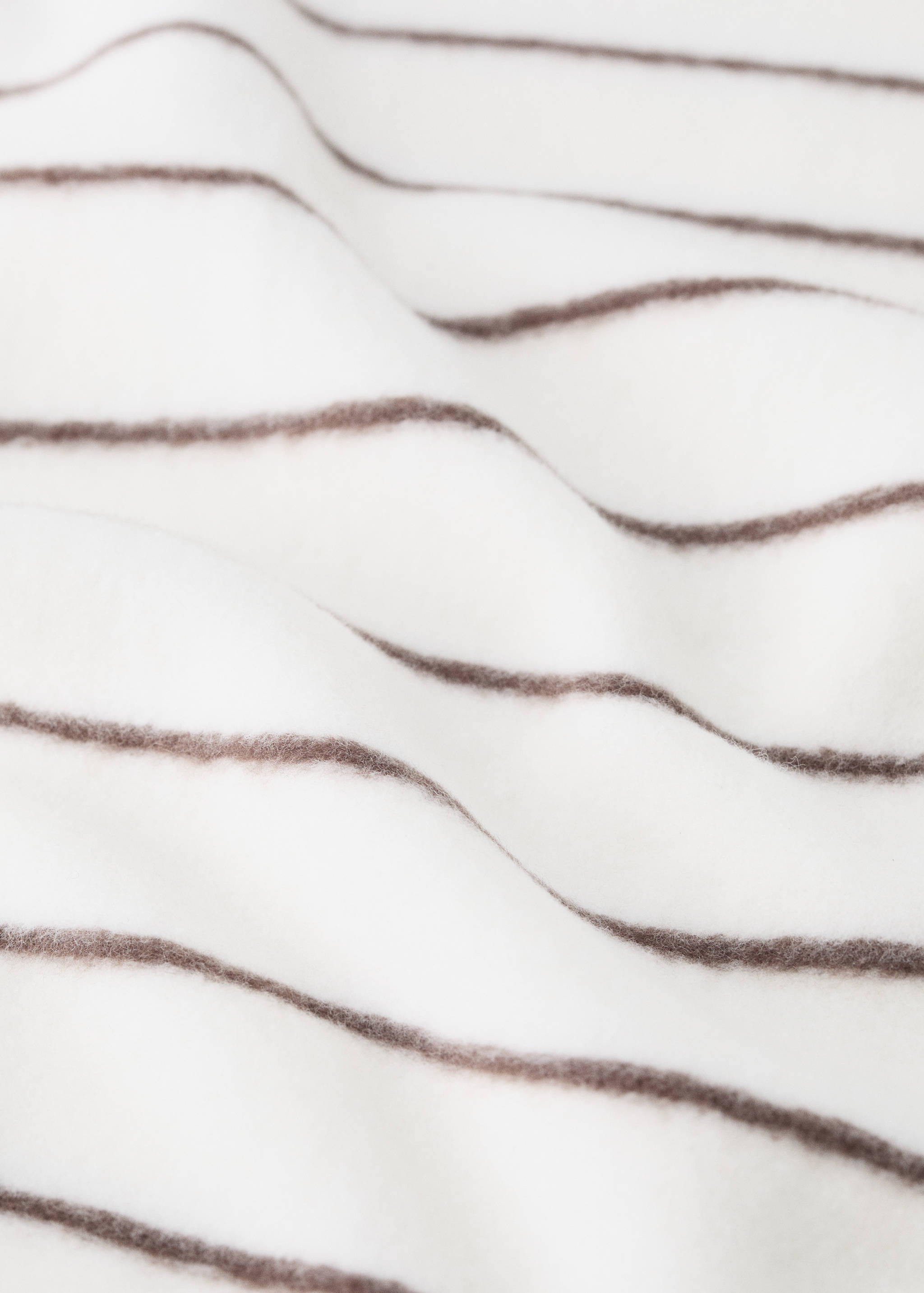 Close-up of a soft white blanket with brown horizontal stripes.