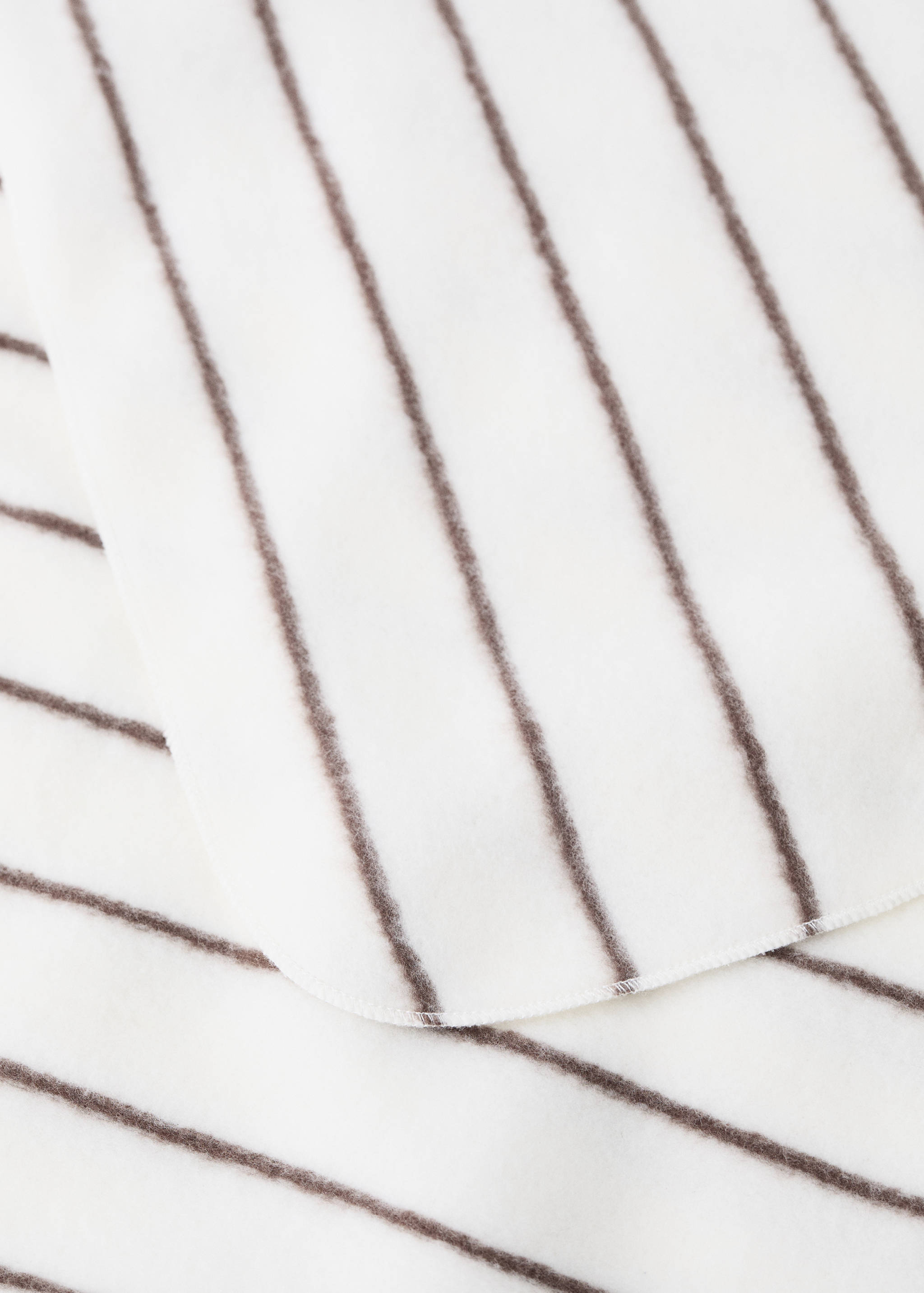 Close-up of a soft white blanket with dark brown vertical stripes.