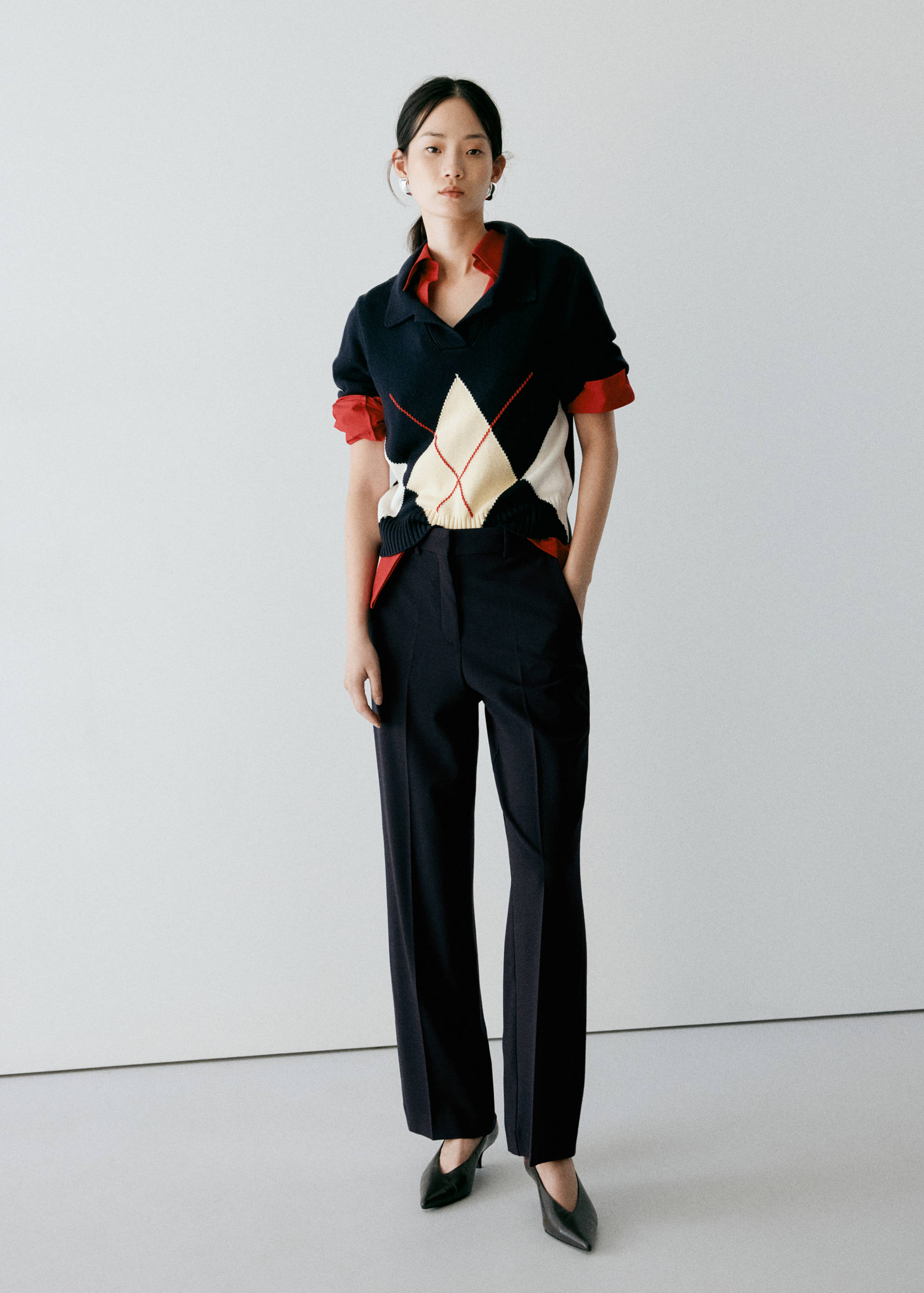 Dark navy blue tailored trousers worn with a patterned knit polo sweater.