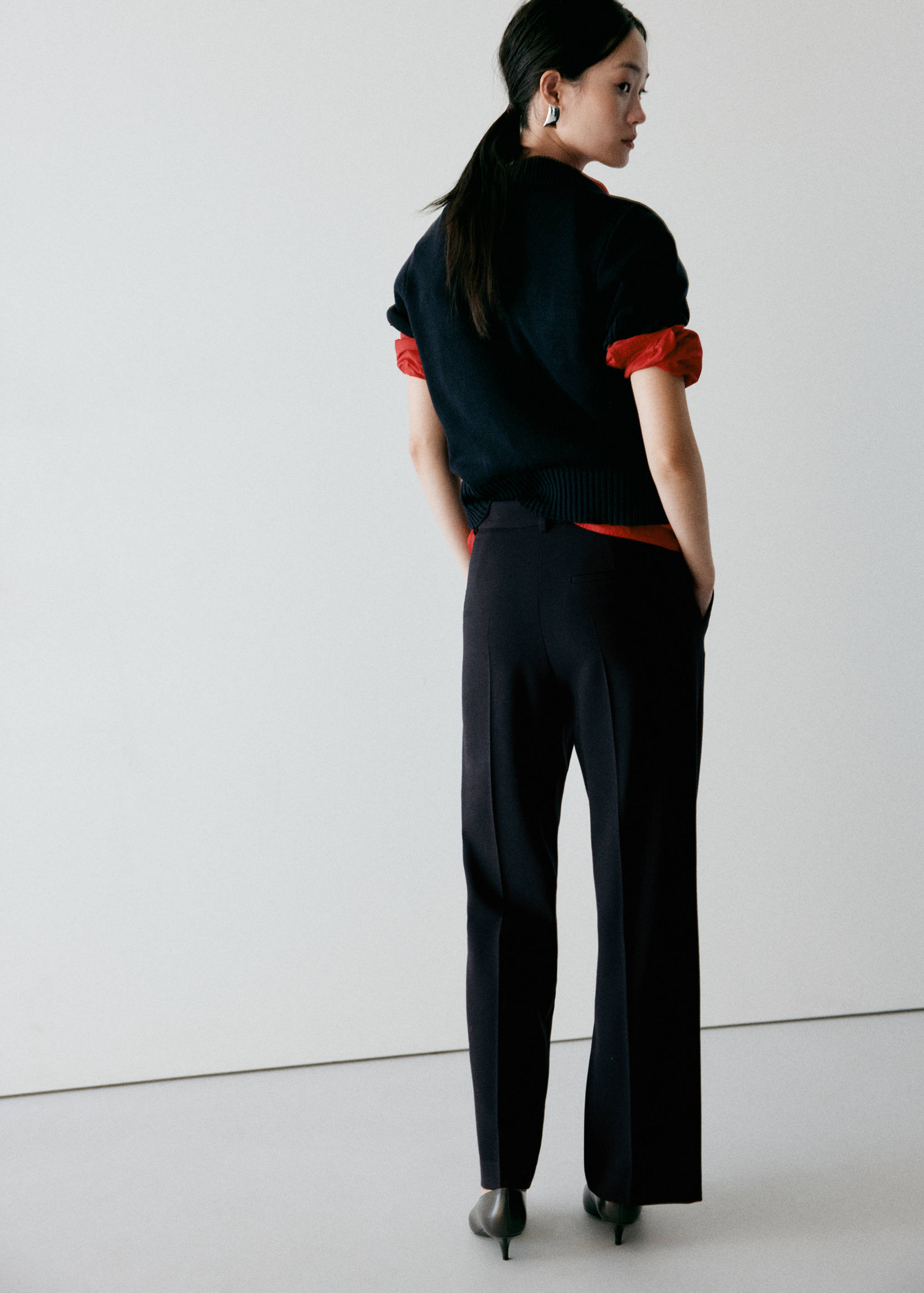 Dark blue trousers seen from the back, featuring pressed center creases.
