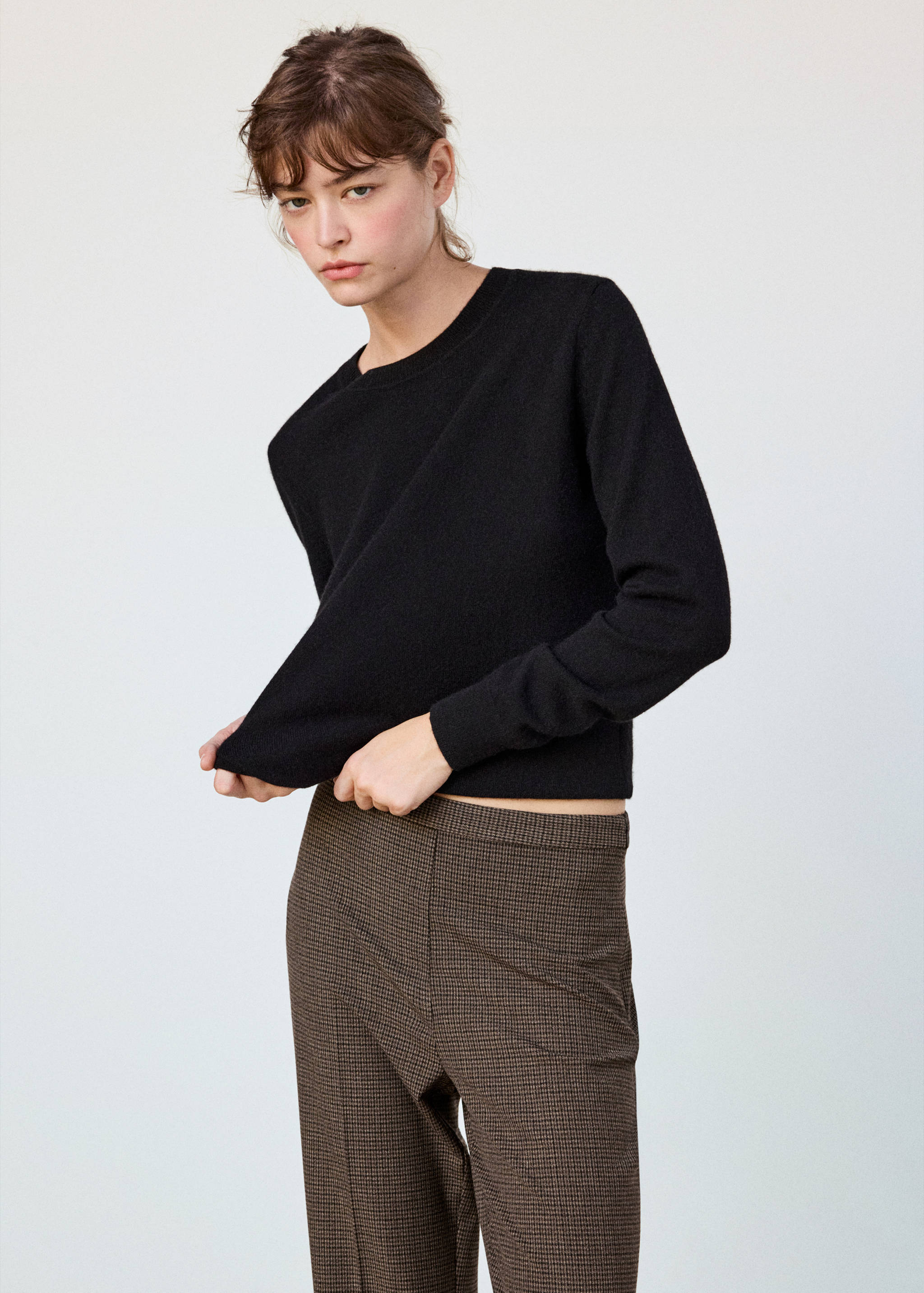 Brown houndstooth trousers worn with a black jumper.