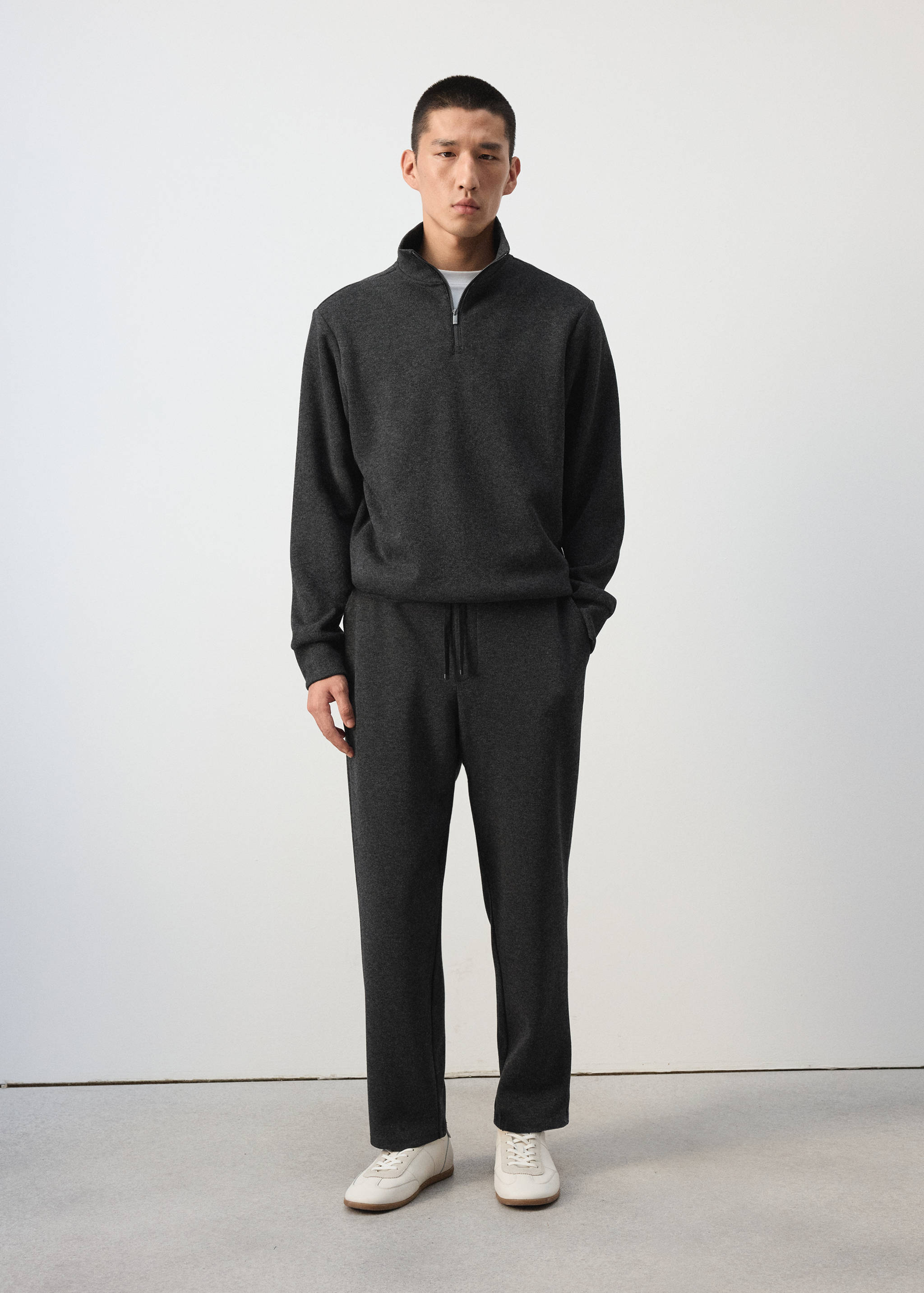 Dark grey zip-collar sweatshirt worn with matching trousers.