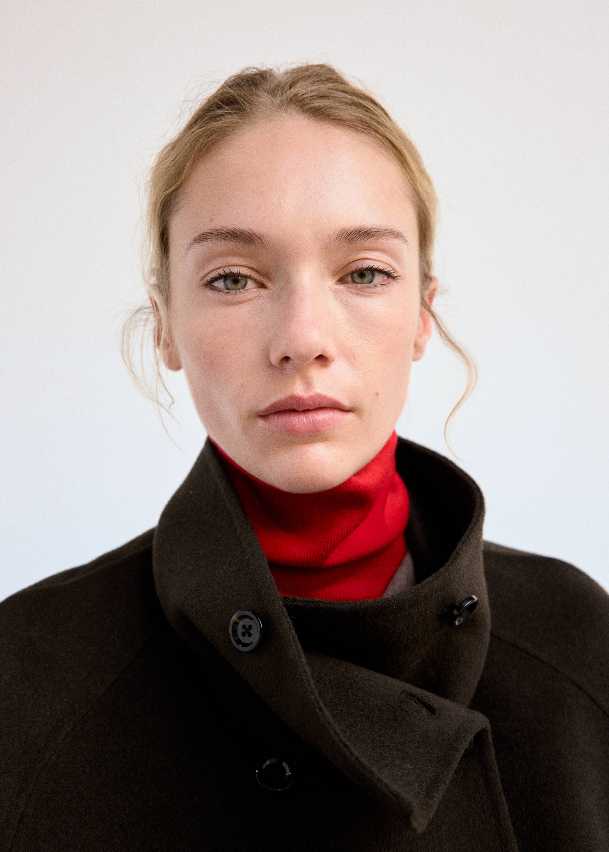 Close-up of a dark green jacket with a high collar over a red turtleneck.