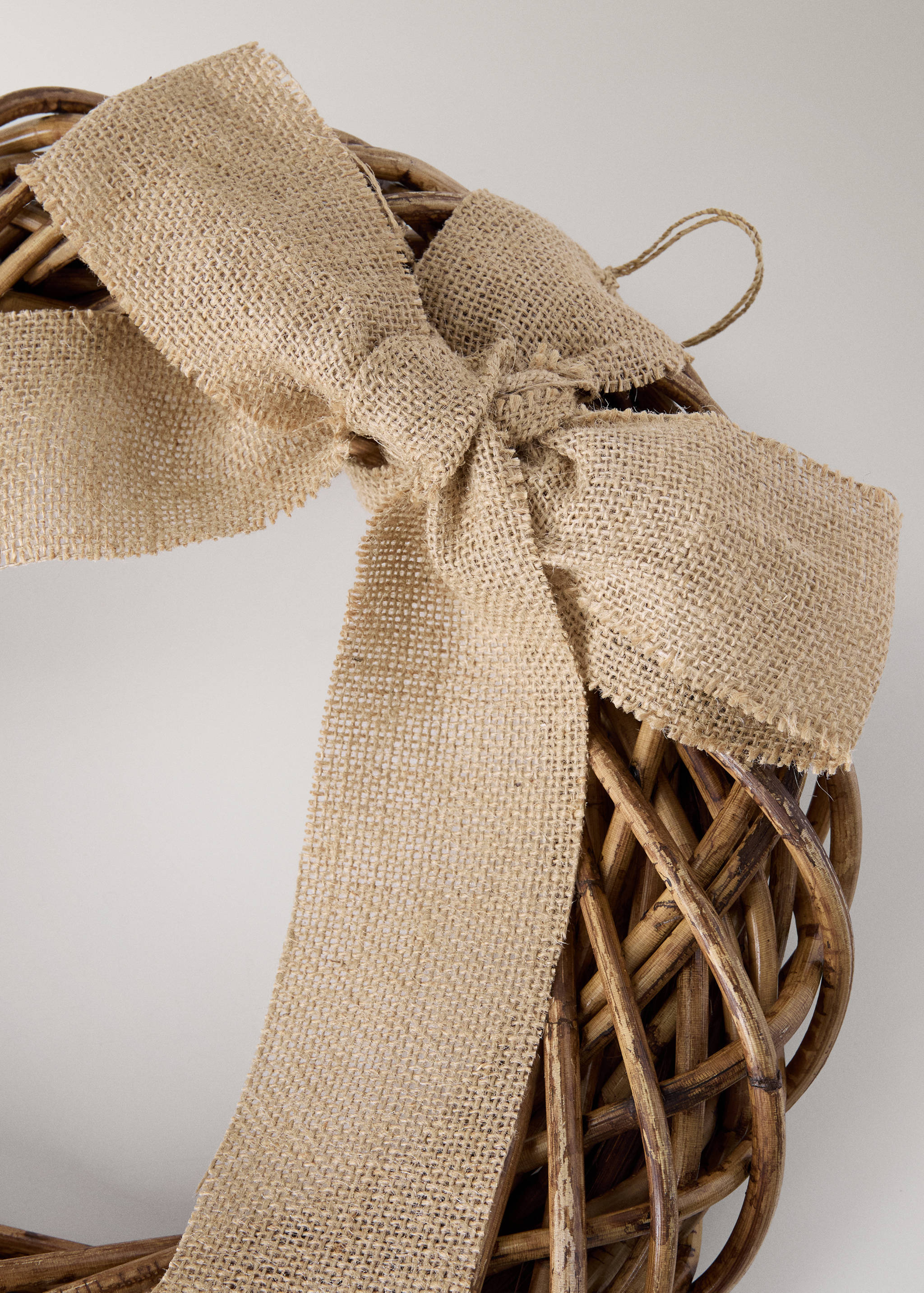 Woven rattan wreath detail with a beige burlap bow.
