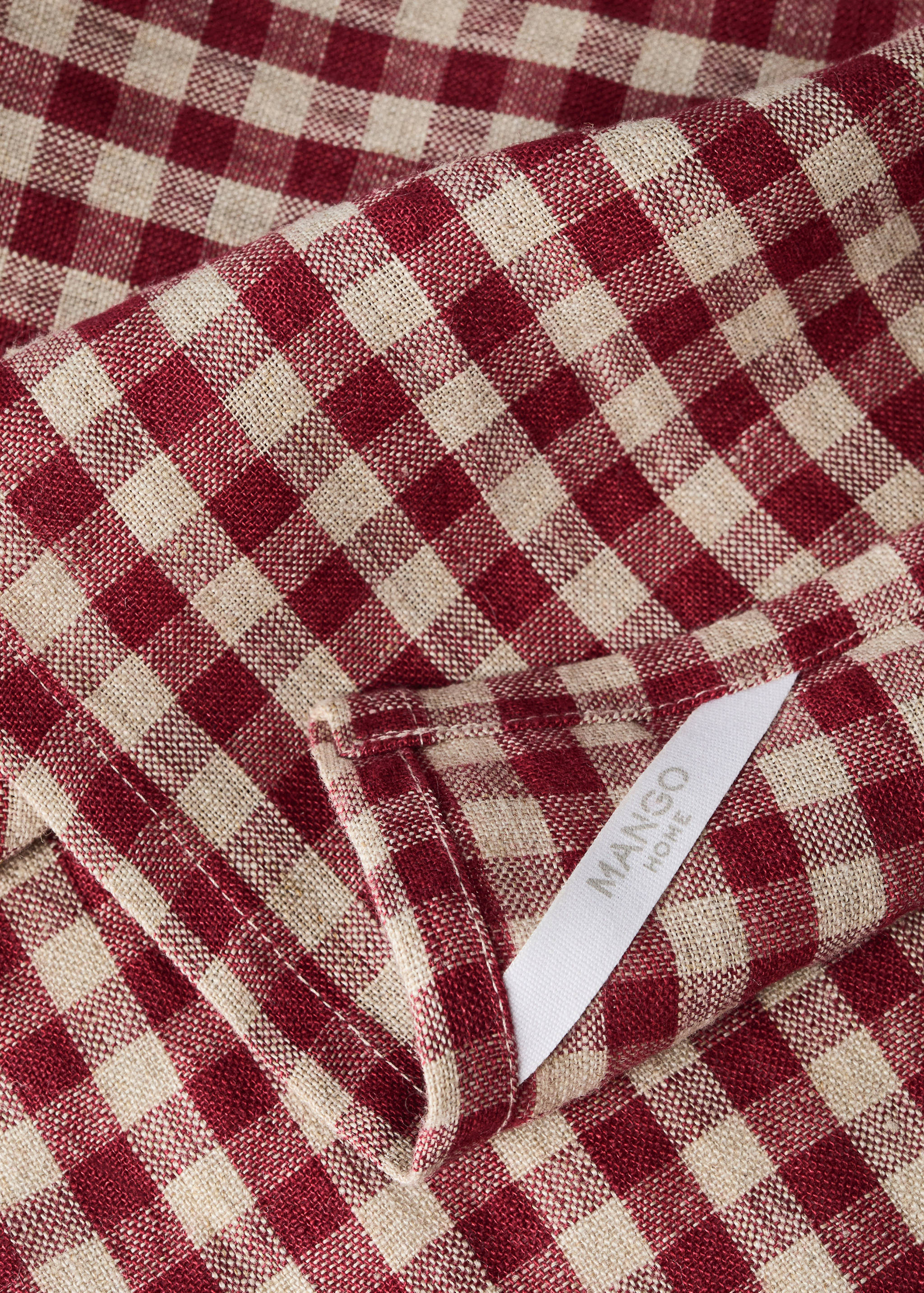 Detalle de trapo de cocina a cuadros en rojo y beige con una etiqueta de Mango Home.