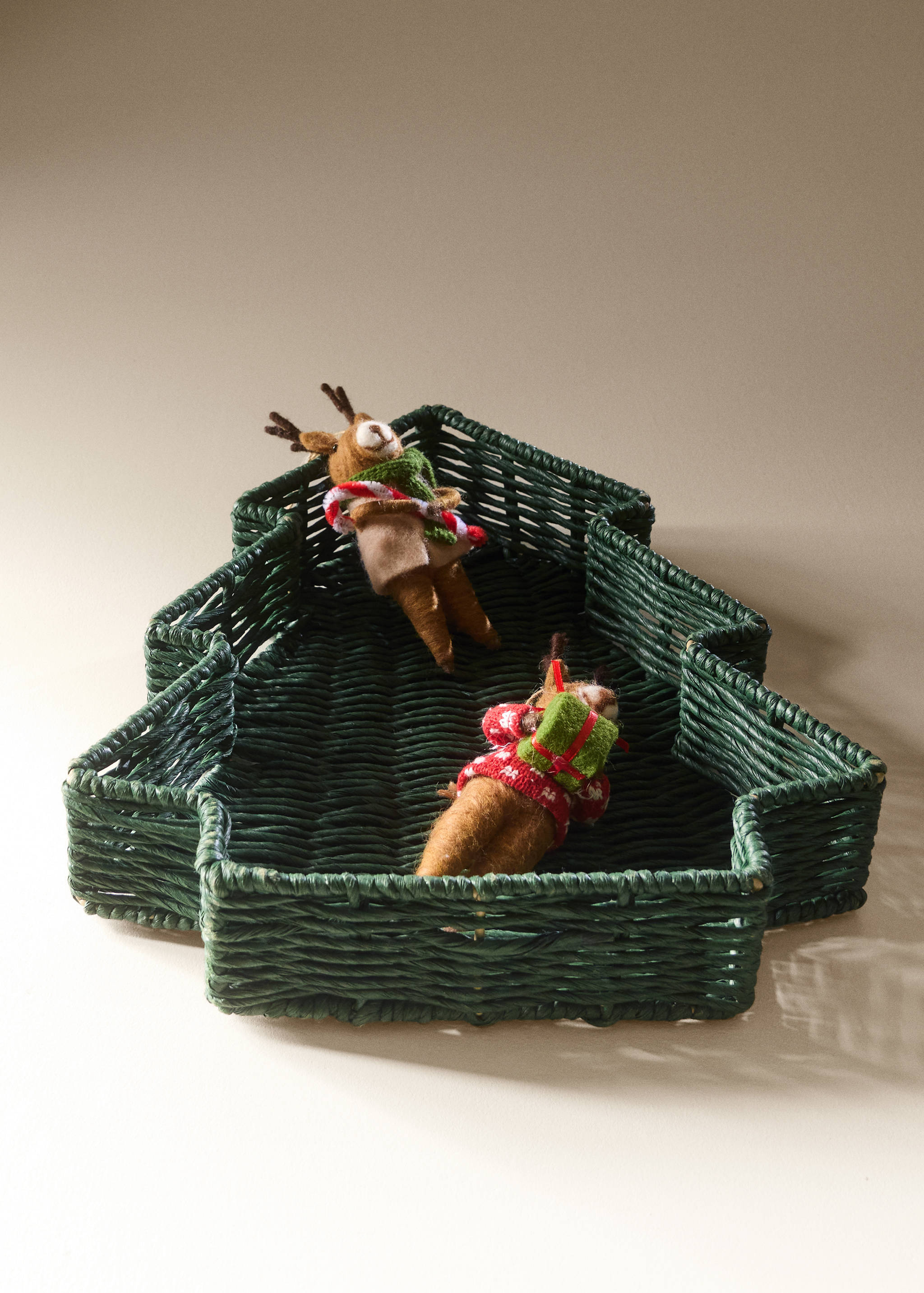 Dark green Christmas tree-shaped woven basket decorated with two felt reindeer figurines.