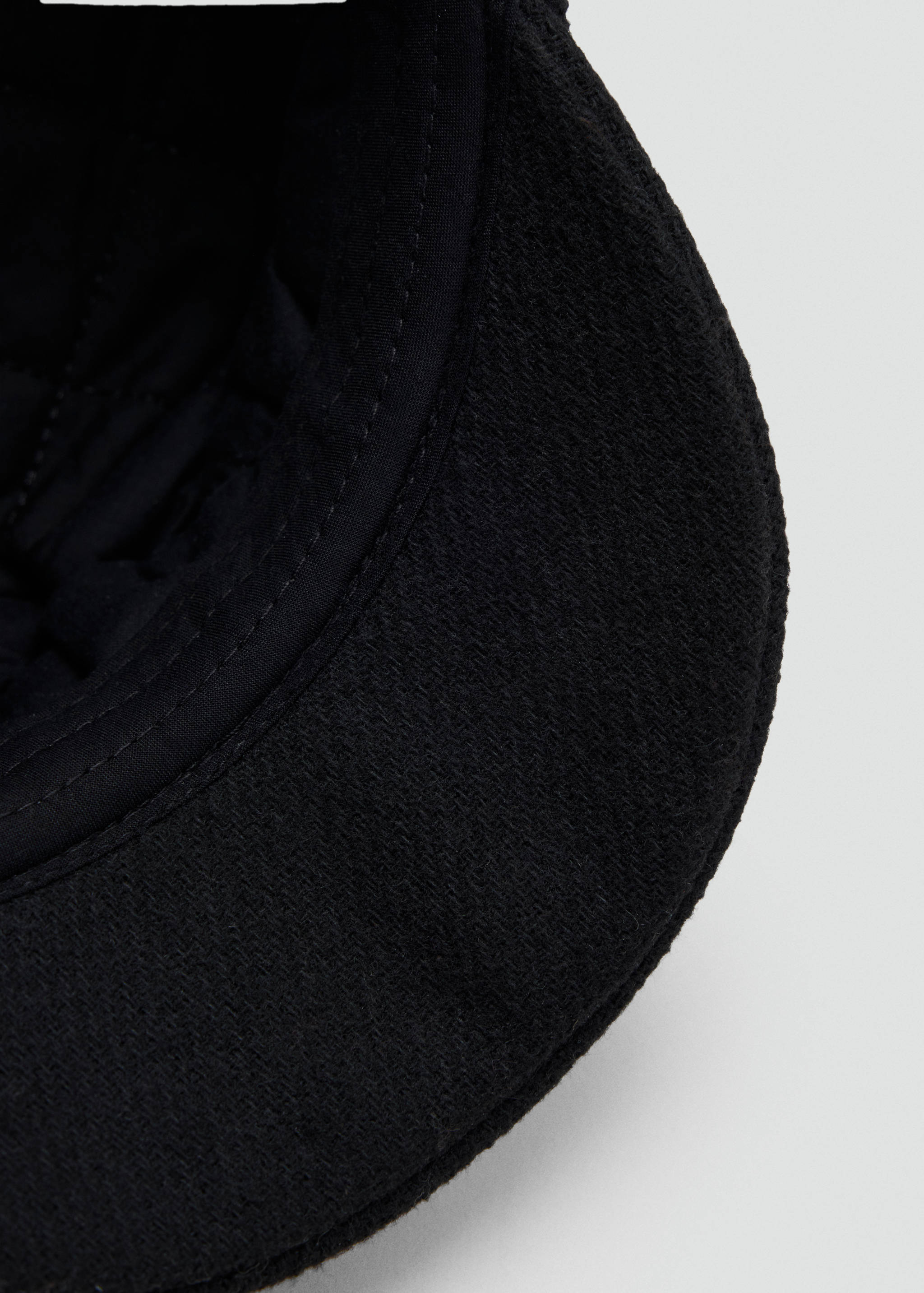 Close-up of a black cap showing its textured brim and interior.