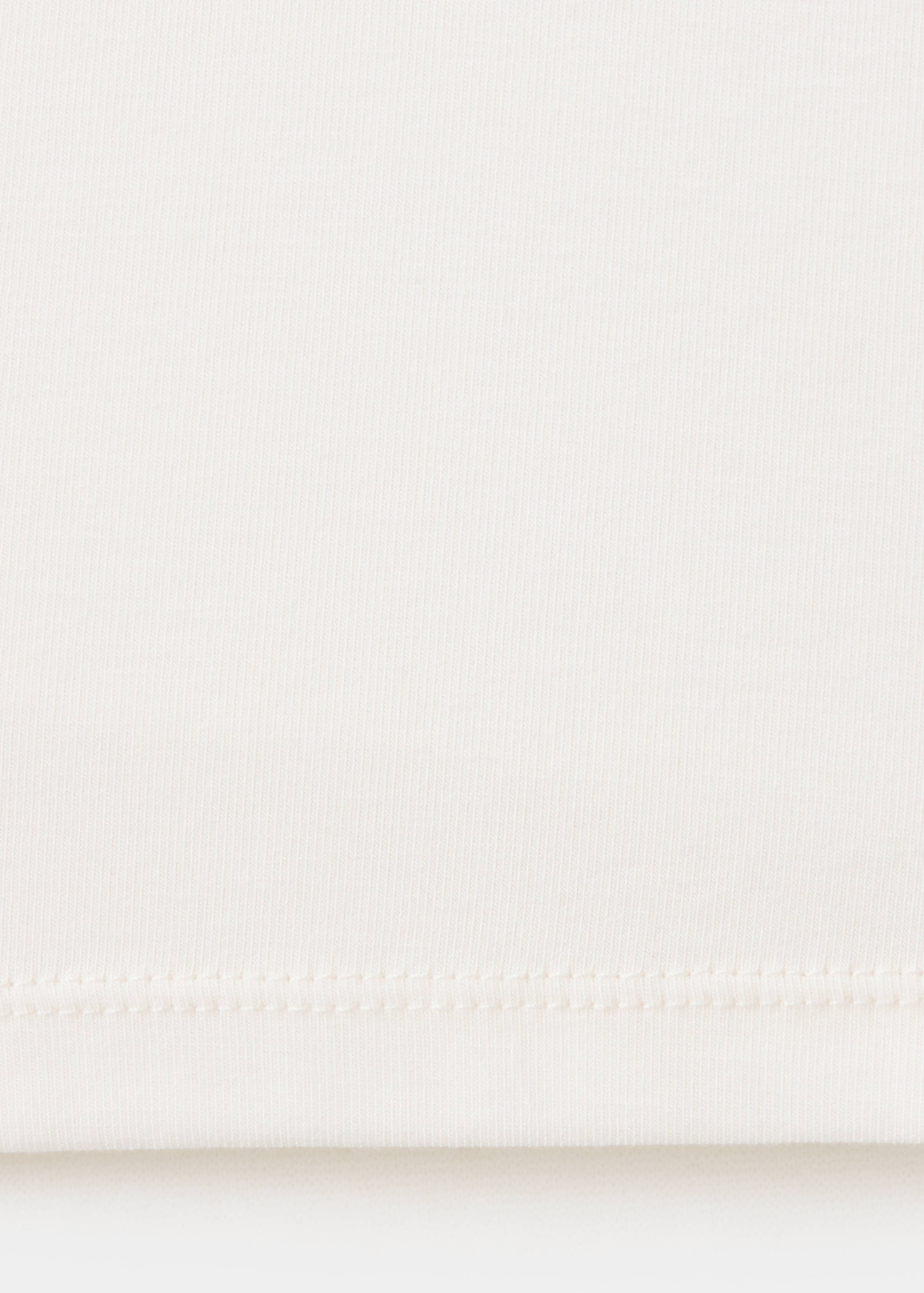 Close-up of the white t-shirt fabric texture and hem.