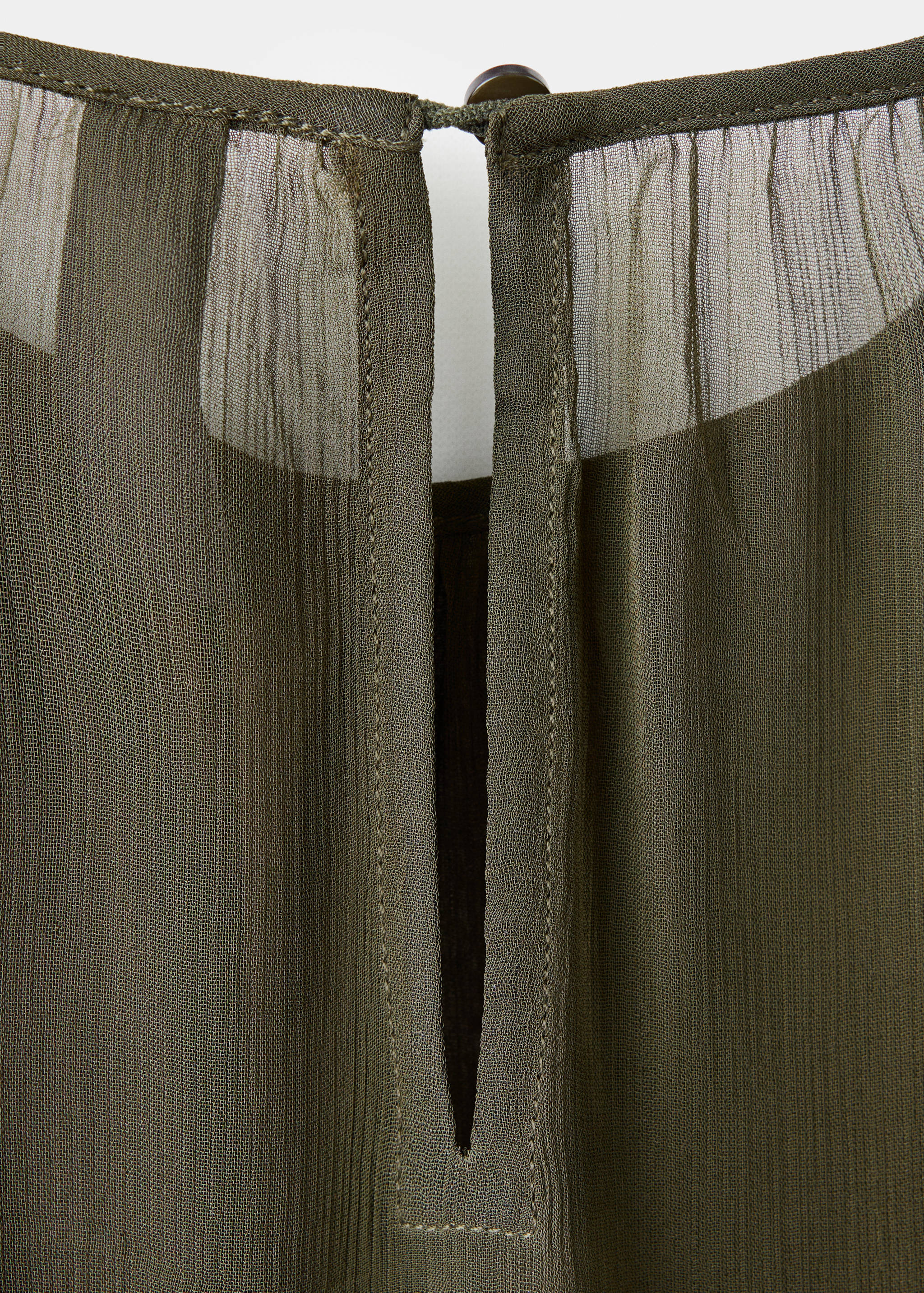 Close-up of the olive green blouse featuring a keyhole back neckline with a button closure.